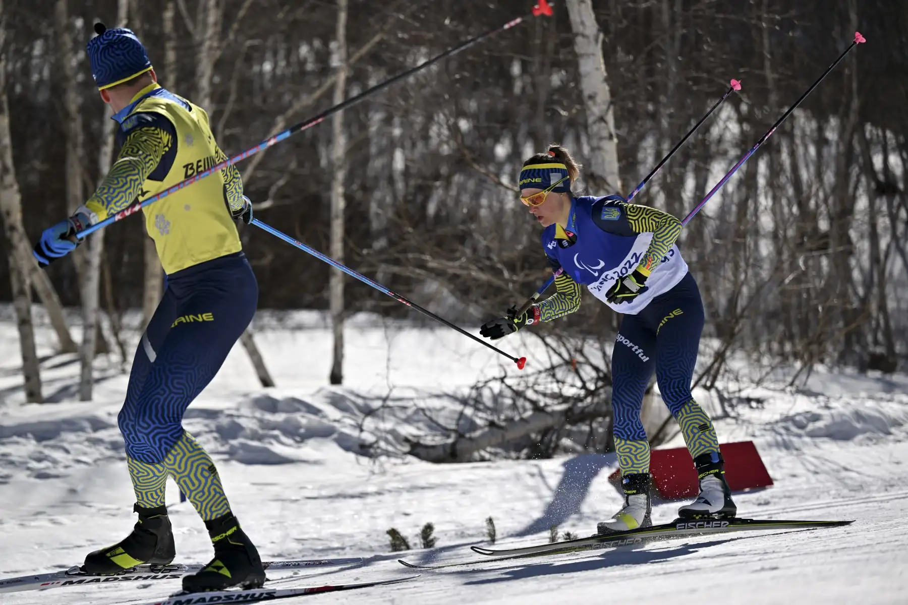 La ucraniana Nataliia Tkachenko agarra el poste de su guía, Denys Nikulin, durante el evento de biatlón para mujeres con problemas de visión, en el Centro Nacional de Biatlón de Zhangjiakou por los Juegos Paralímpicos de Invierno de Beijing 2022. Foto: AFP