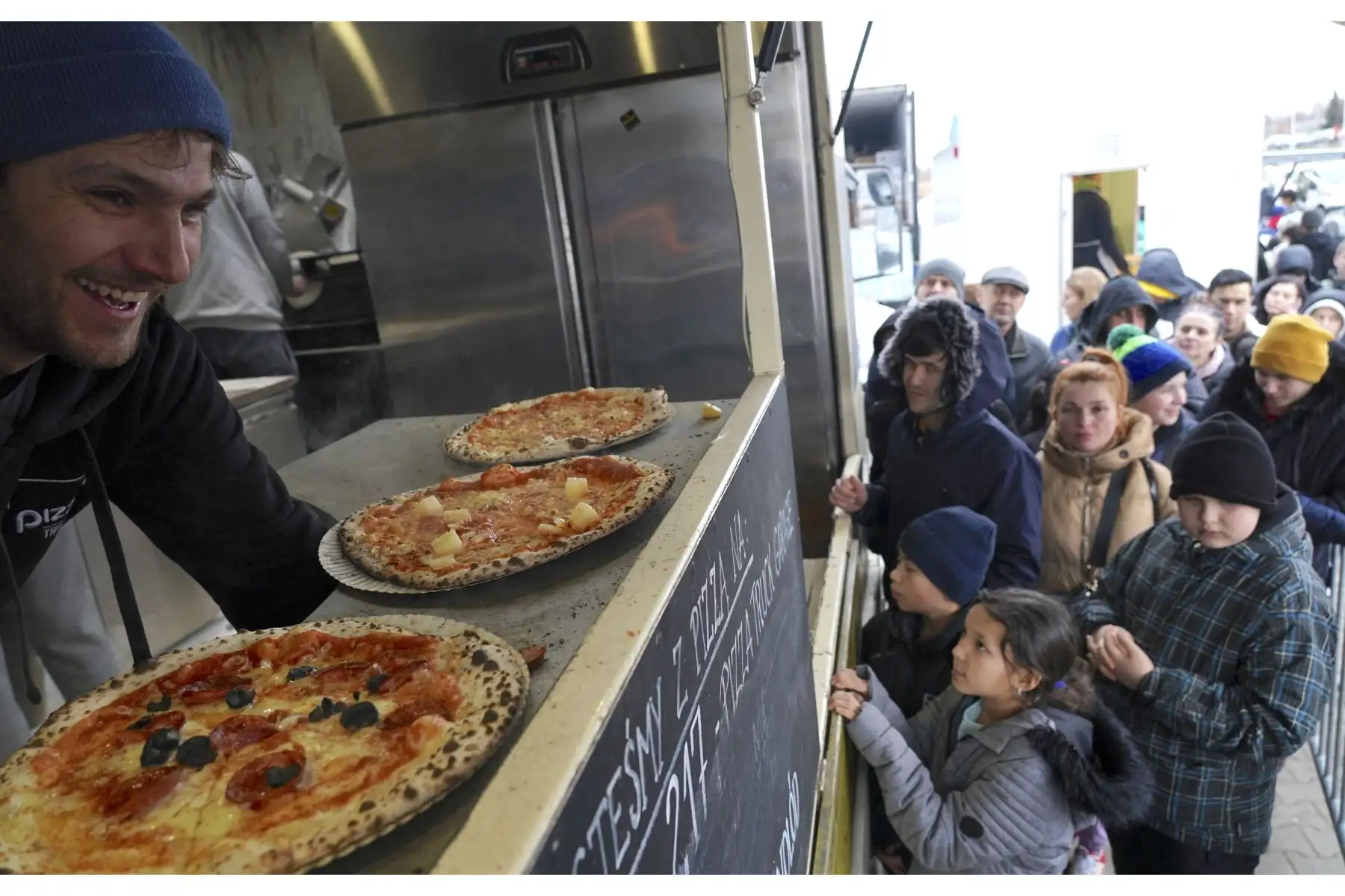 El dueño de un camión de comida distribuye pizzas gratis a los refugiados ucranianos, en el centro de distribución de refugiados en Korczowa, Polonia. Foto: AFP