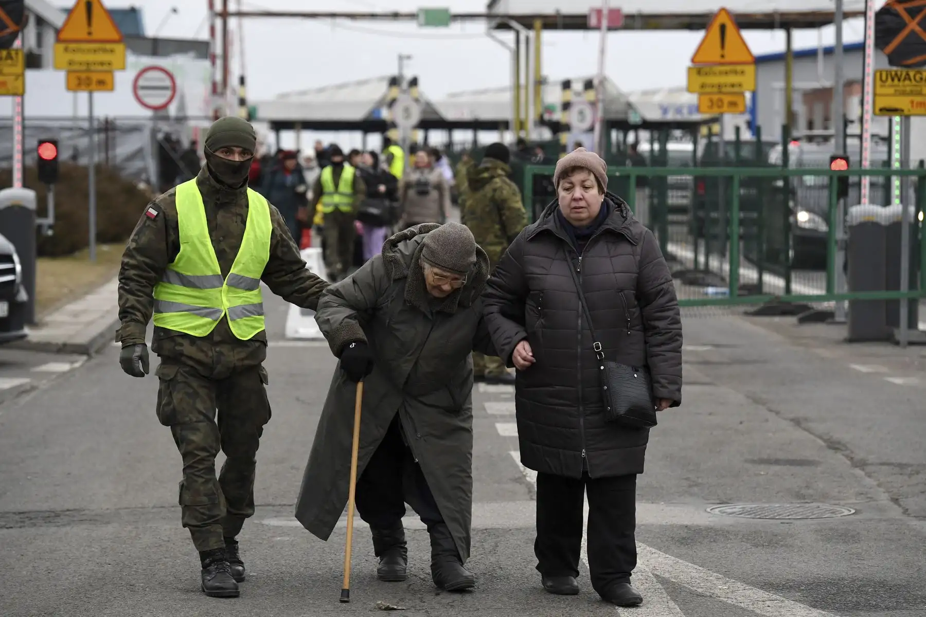 Un hombre polaco ayuda a los ancianos que vienen de Ucrania, mientras cruzan la frontera ucraniano-polaca en Korczowa, Polonia. Foto: AFP