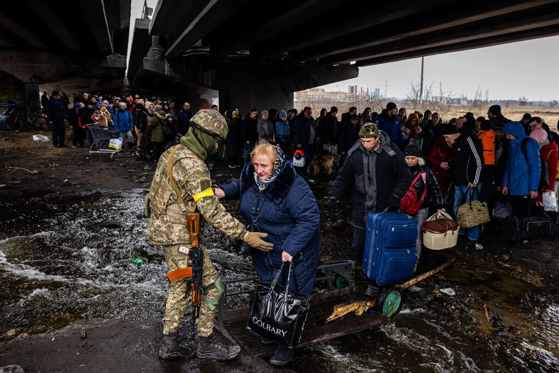 Un militar ucraniano ayuda a los evacuados reunidos bajo un puente destruido, mientras huyen de la ciudad de Irpin, al noroeste de Kiev.
Foto: AFP