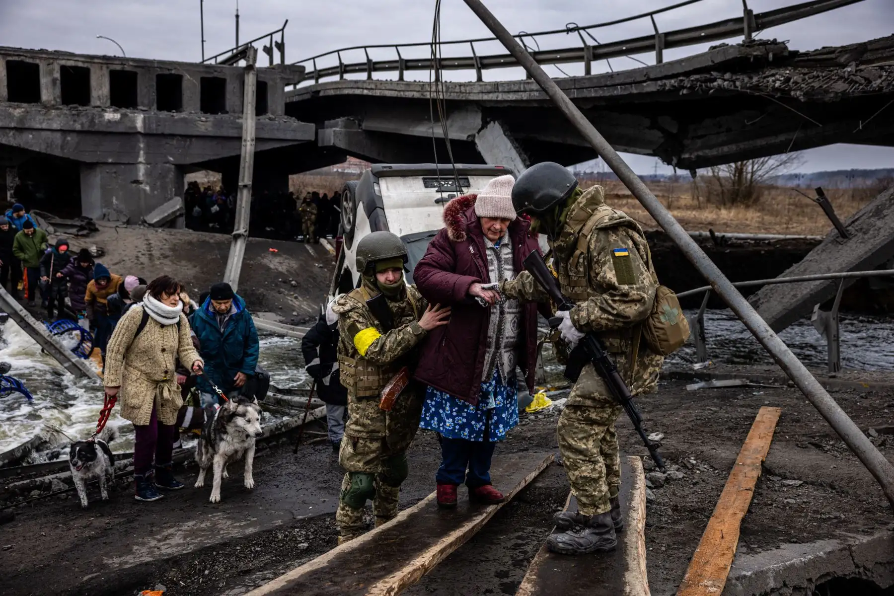 Soldados ucranianos ayudan a una anciana a cruzar un puente destruido mientras evacua la ciudad de Irpin, al noroeste de Kiev.
Foto: AFP