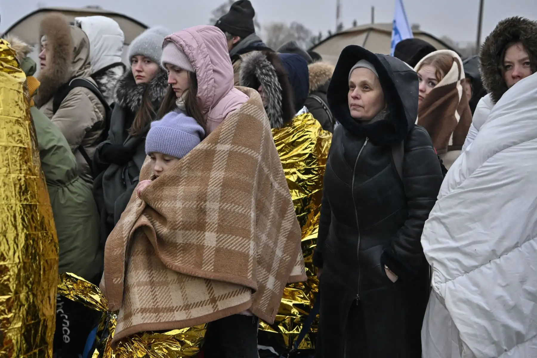 Refugiados envueltos en mantas hacen fila en el frío mientras esperan ser trasladados a una estación de tren después de cruzar la frontera de Ucrania hacia Polonia, en el cruce fronterizo de Medyka en Polonia.
Foto: AFP