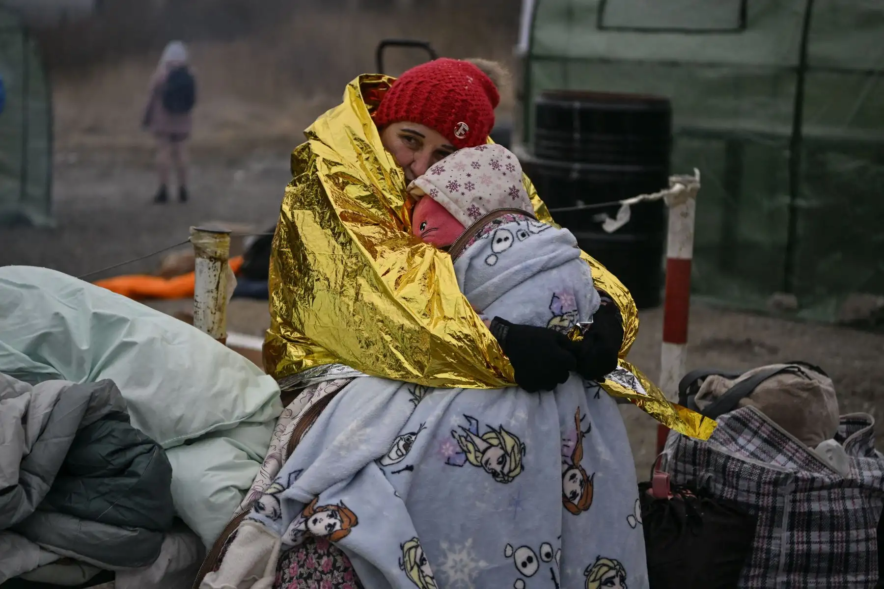 Una mujer abraza a su nieta mientras la gente espera bajo temperaturas heladas para ser trasladada a una estación de tren, después de cruzar la frontera de Ucrania hacia Polonia, en el cruce fronterizo de Medyka en Polonia.
Foto: AFP