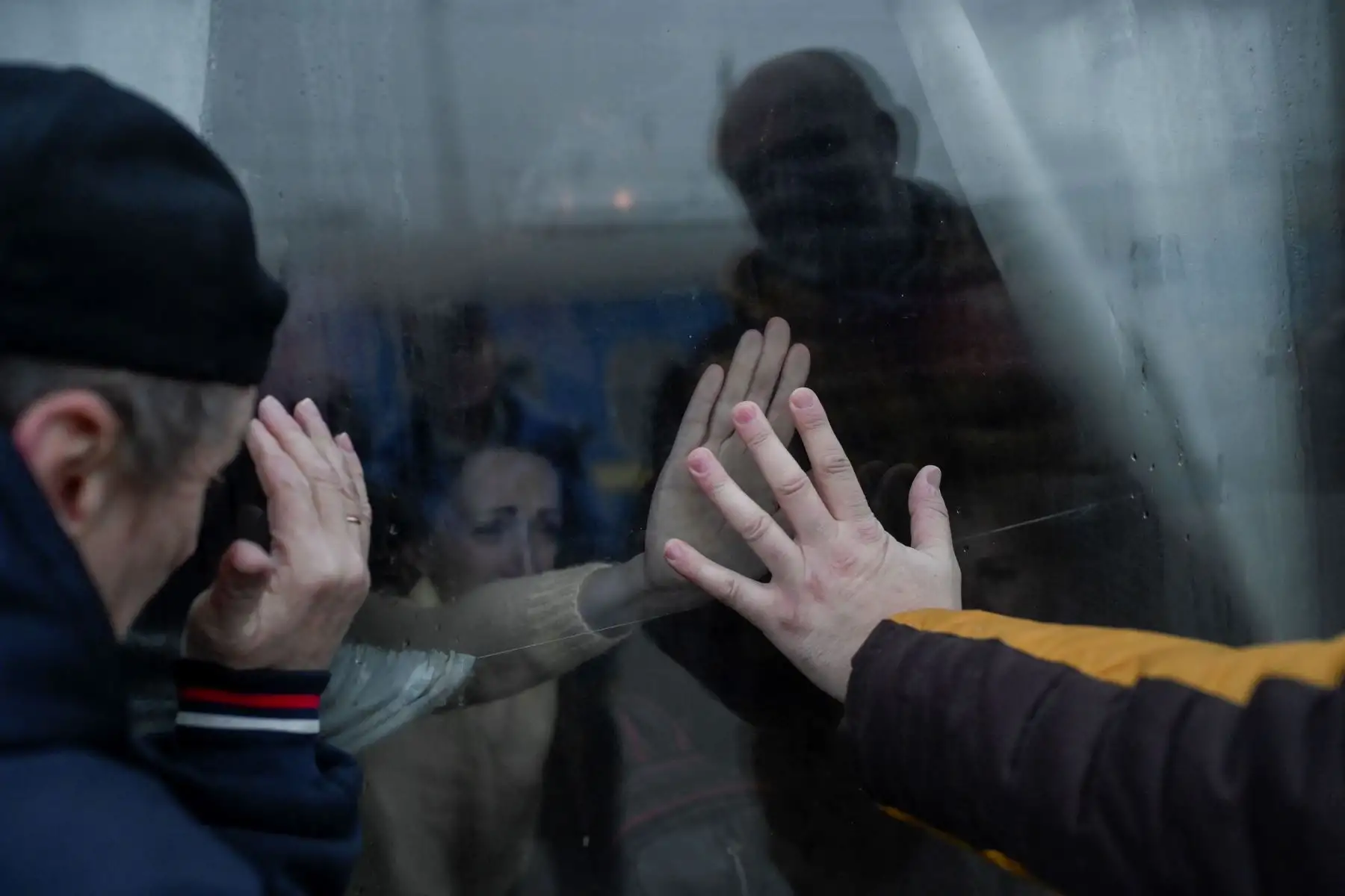 Un padre se da la mano con su familia a través de la ventana mientras se despide frente a un tren de evacuación en la estación central de Odessa.
Foto: AFP