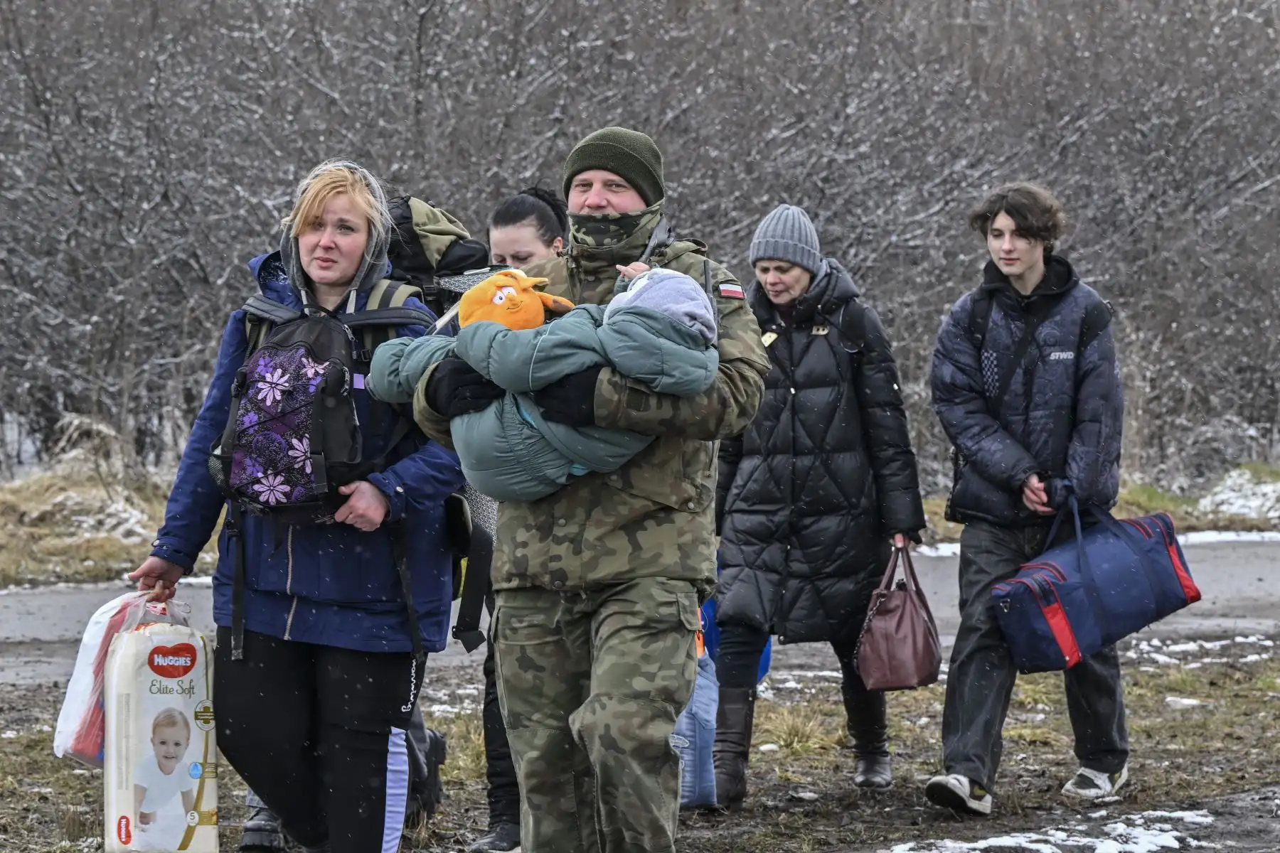 Un soldado polaco carga a un niño y ayuda a una familia de refugiados después de que cruzaron la frontera a Polonia desde Ucrania en el cruce fronterizo de Medyka, al este de Polonia. Foto: AFP