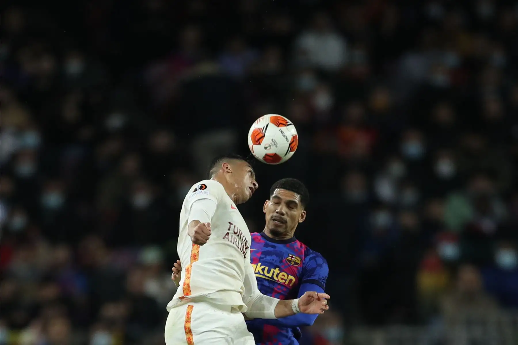 El delantero del Galatasaray Mostafa Mohamed  cabecea un balón ante Ronald Araújo, del FC Barcelona, durante el partido de ida de los octavos de final de la Liga Europa que disputan hoy en el Camp Nou, en Barcelona. 
Foto: EFE