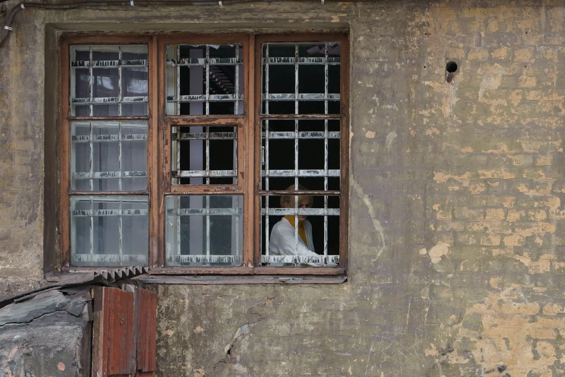 Una mujer detrás de la ventana rota de un edificio residencial dañado en un ataque aéreo en Dnipro. Foto: AFP