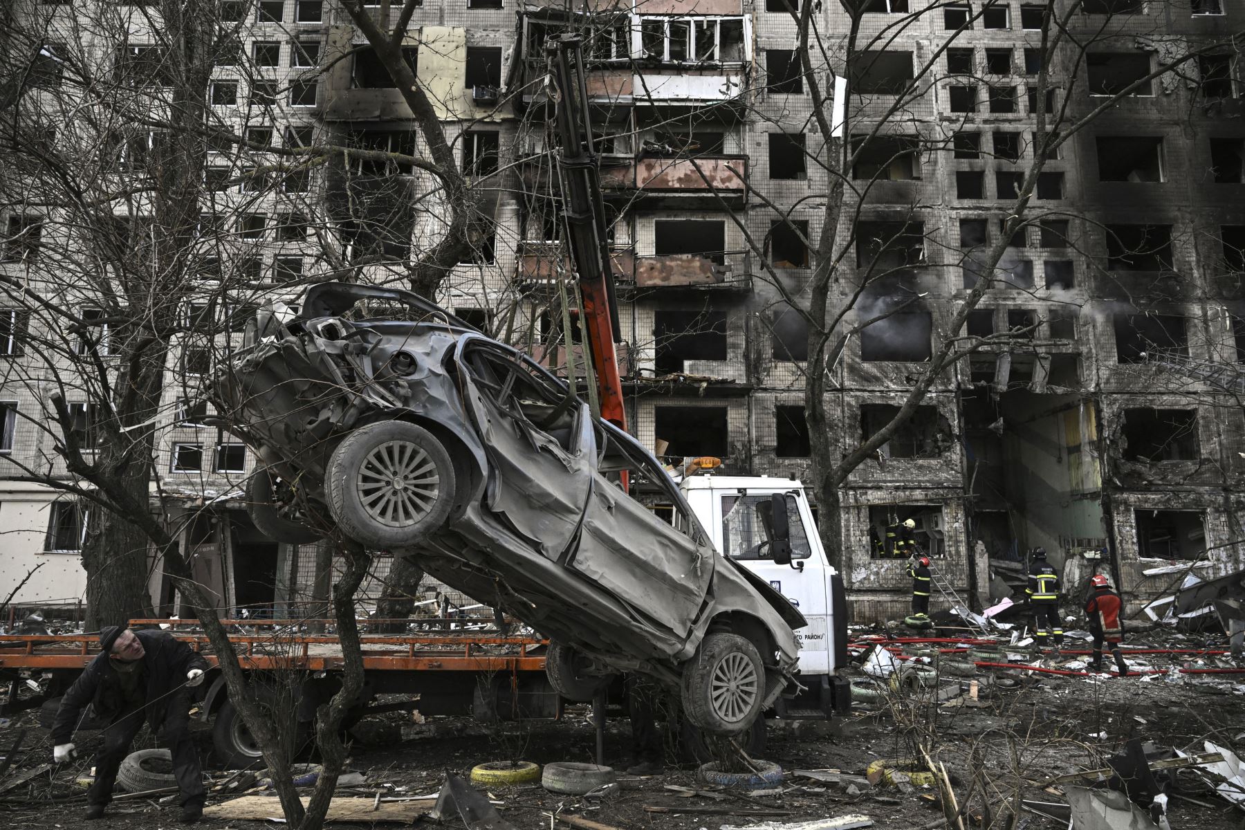 Una grúa retira un automóvil arruinado frente a un edificio de apartamentos destruido después de que fue bombardeado en el distrito noroccidental de Obolon en Kiev.
Foto: AFP