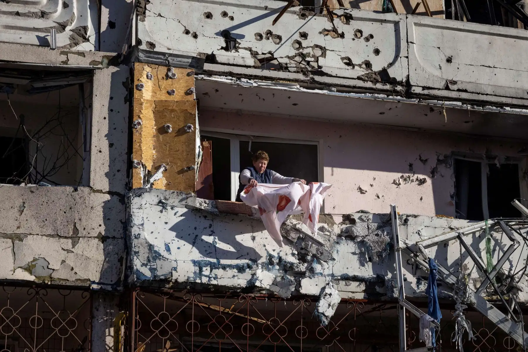 Una residente limpia su balcón en un edificio residencial dañado por los bombardeos en Kiev, después de que los ataques mataran al menos a dos personas, dijeron los servicios de emergencia de Ucrania. Foto: AFP