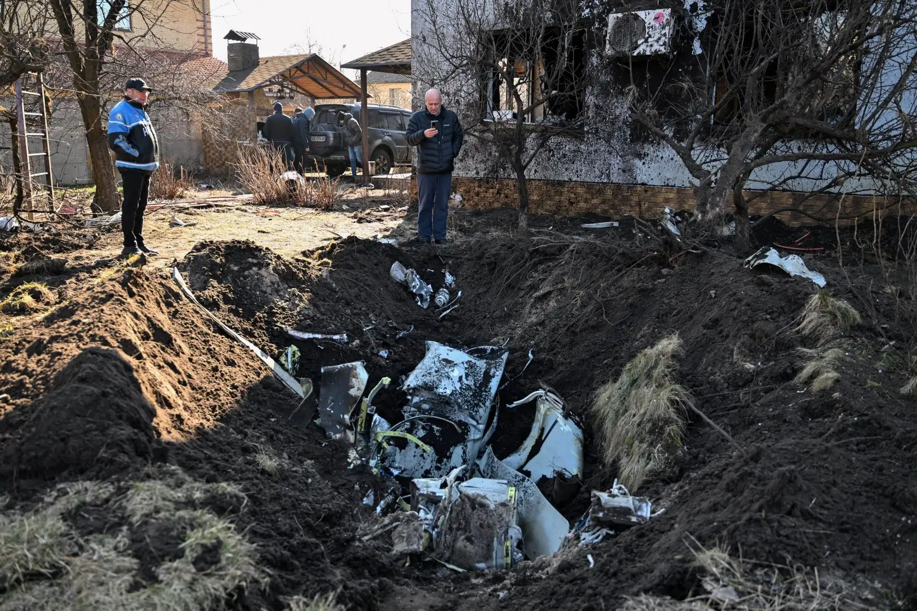 Un hombre toma fotografías de los restos de un misil en el patio de una casa privada atacada por bombardeos en el distrito de Osokorky en el sureste de Kiev. Foto: AFP