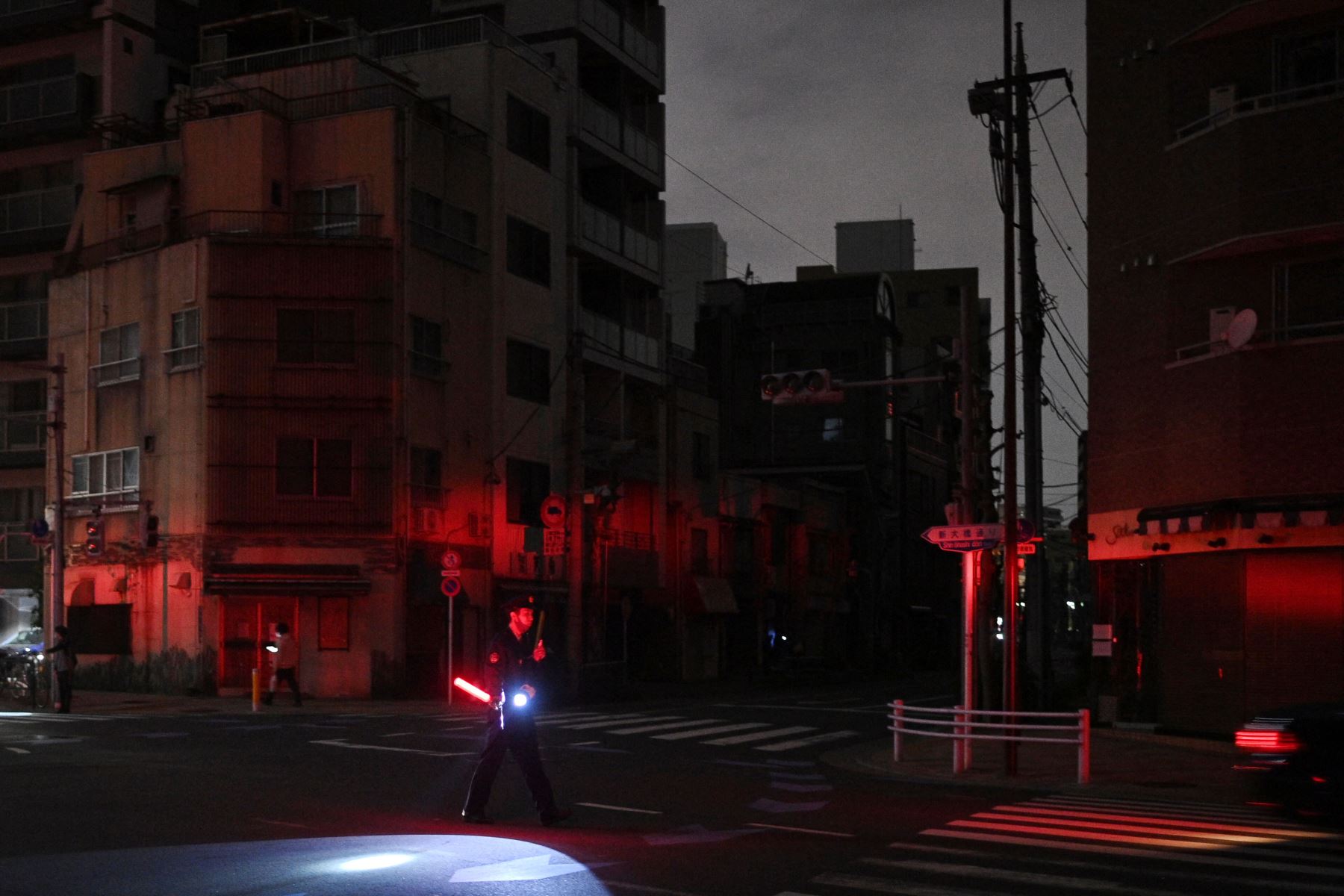 Un policía se para junto al tráfico directo de una calle durante un corte de energía en Tokio a primeras horas del 17 de marzo de 2022, después de que un poderoso terremoto de magnitud 7,3 sacudiera el este de Japón.
Foto:  AFP