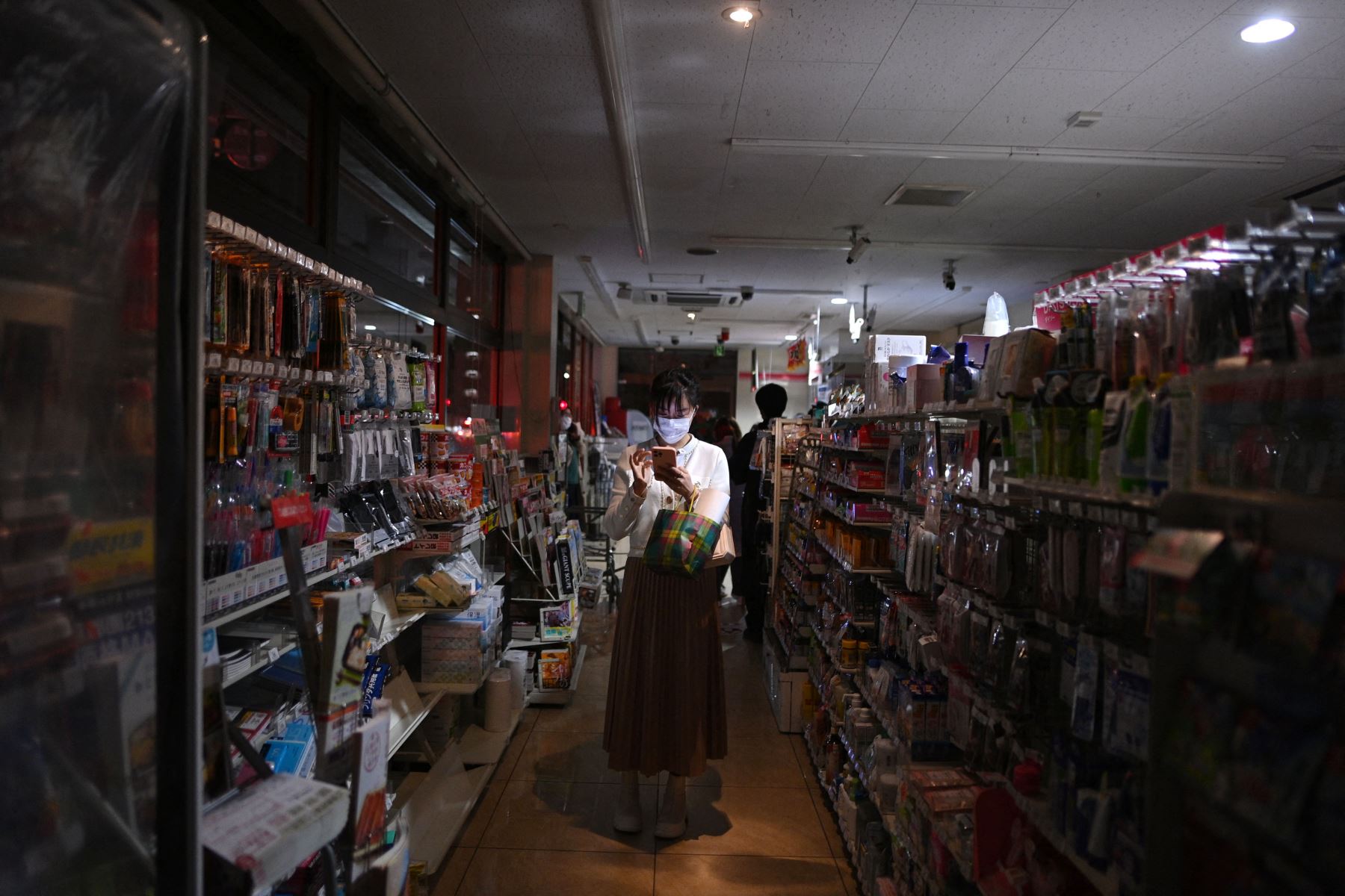 Una mujer compra en una tienda en un área residencial durante un corte de energía en el distrito de Koto , luego de que un poderoso terremoto de magnitud 7.3 sacudiera el este de Japón.
Foto: AFP