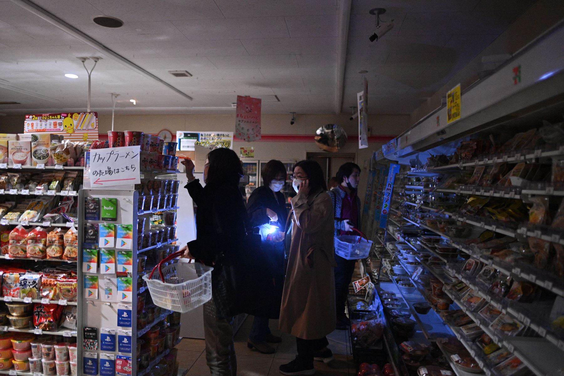 La gente compra en una tienda en un área residencial durante un corte de energía en el distrito de Koto, luego de que un poderoso terremoto de magnitud 7.3 sacudiera el este de Japón.
Foto: AFP