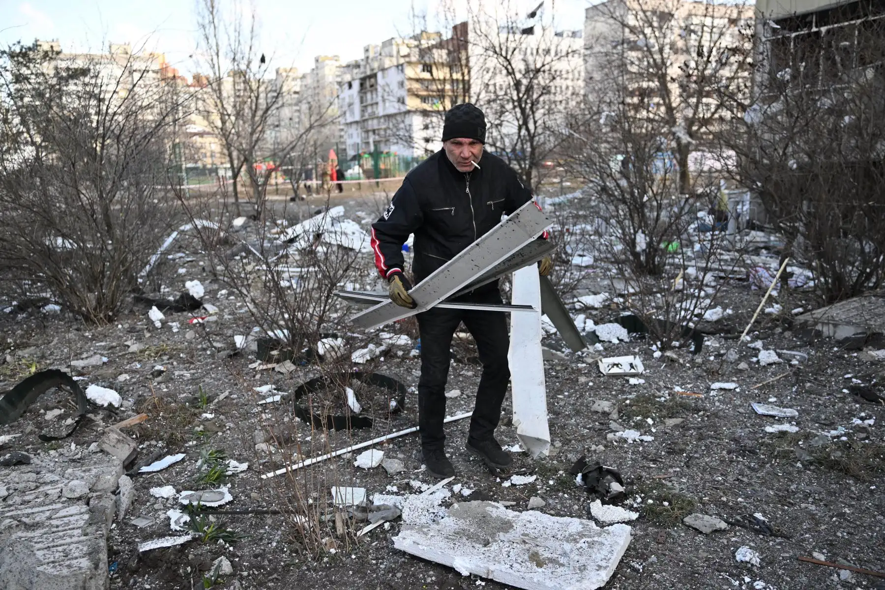 Un hombre recoge los escombros fuera de un bloque de viviendas dañado después de que fue alcanzado por los escombros de un cohete derribado en Kiev. Foto: AFP