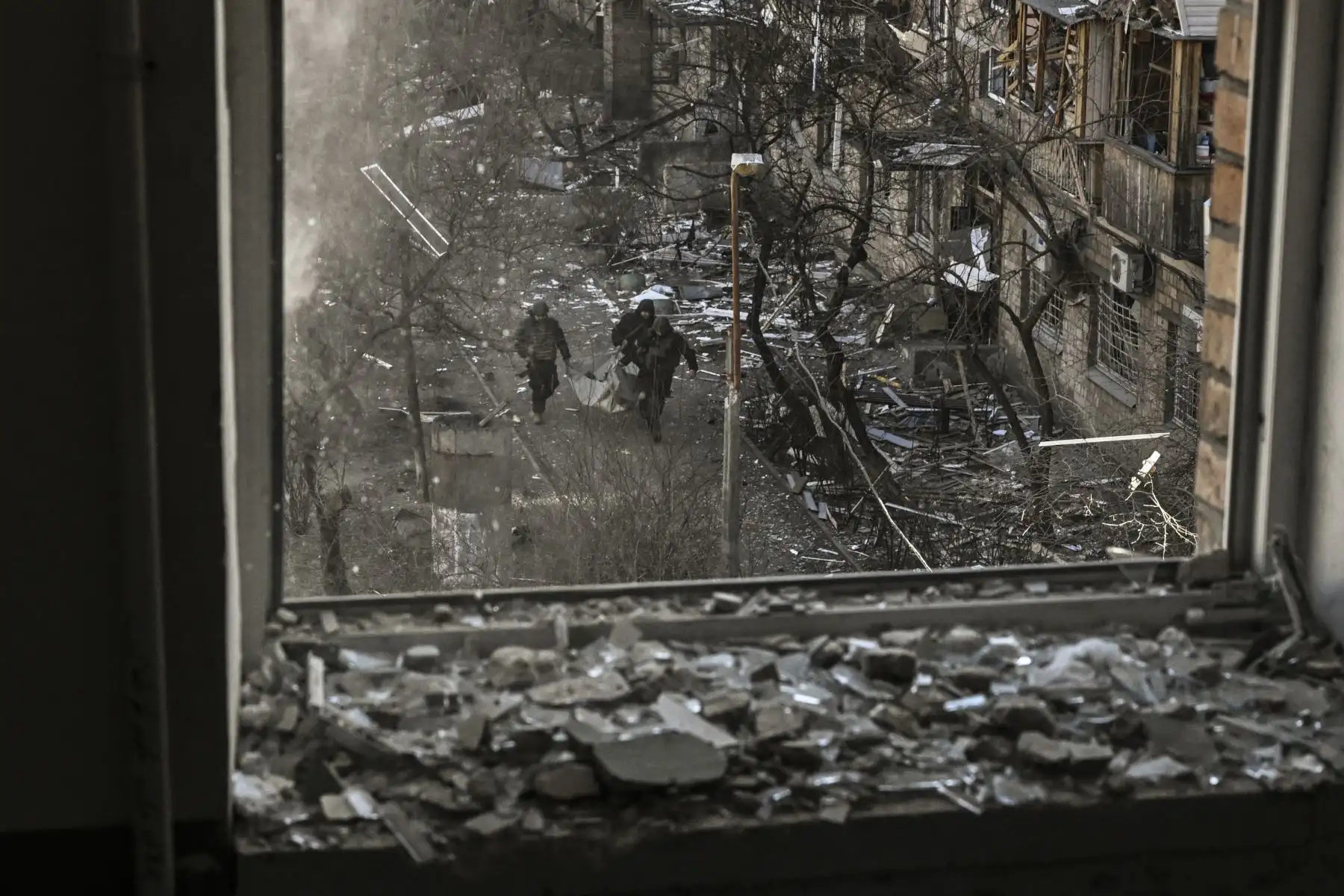 Militares ucranianos a través de la ventana de un edificio mientras llevan los restos de un misil después de bombardear una zona residencial en Kiev. Foto: AFP