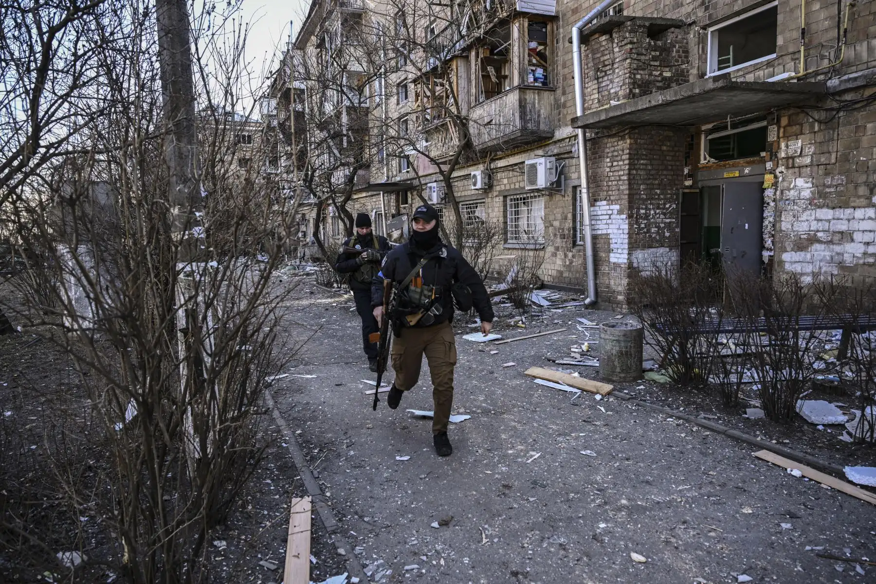 Militares ucranianos corren frente a un edificio de apartamentos destruido en una zona residencial después de un bombardeo en Kiev. Foto: AFP