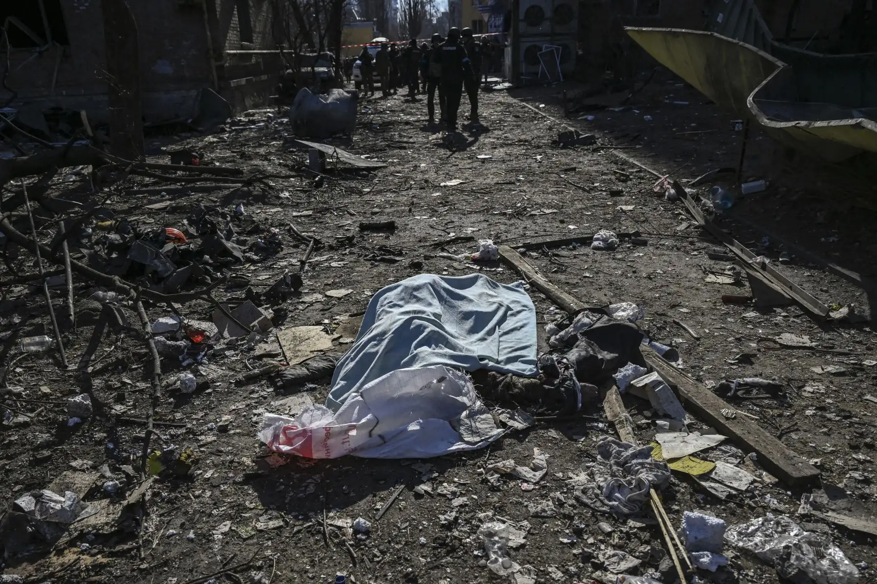 Un cuerpo cubierto con una manta yace entre los daños en una zona residencial después de un bombardeo en Kiev. Foto: AFP
