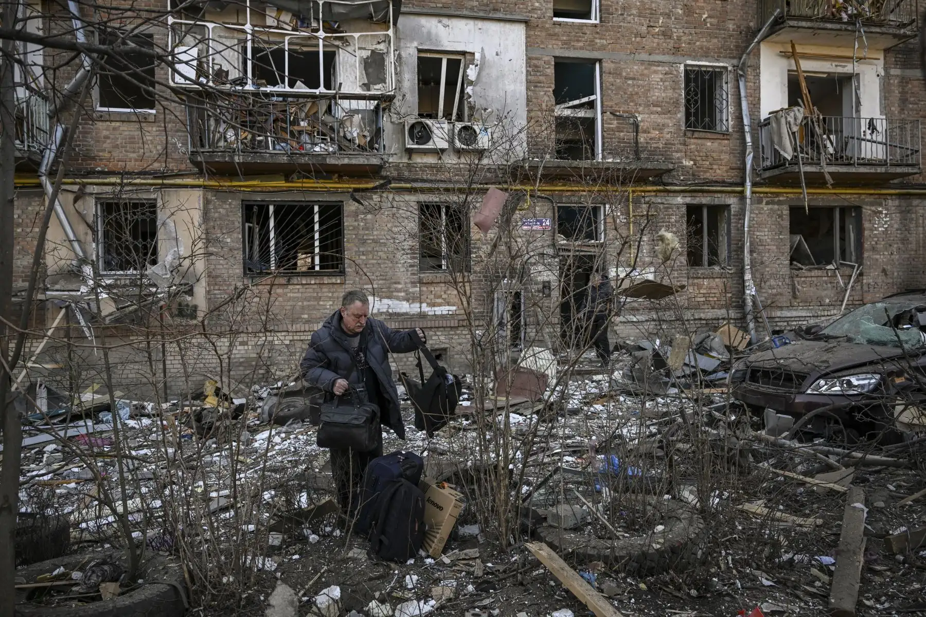 Un hombre lleva pertenencias de un edificio de apartamentos destruido en una zona residencial después de un bombardeo en Kiev. Foto: AFP