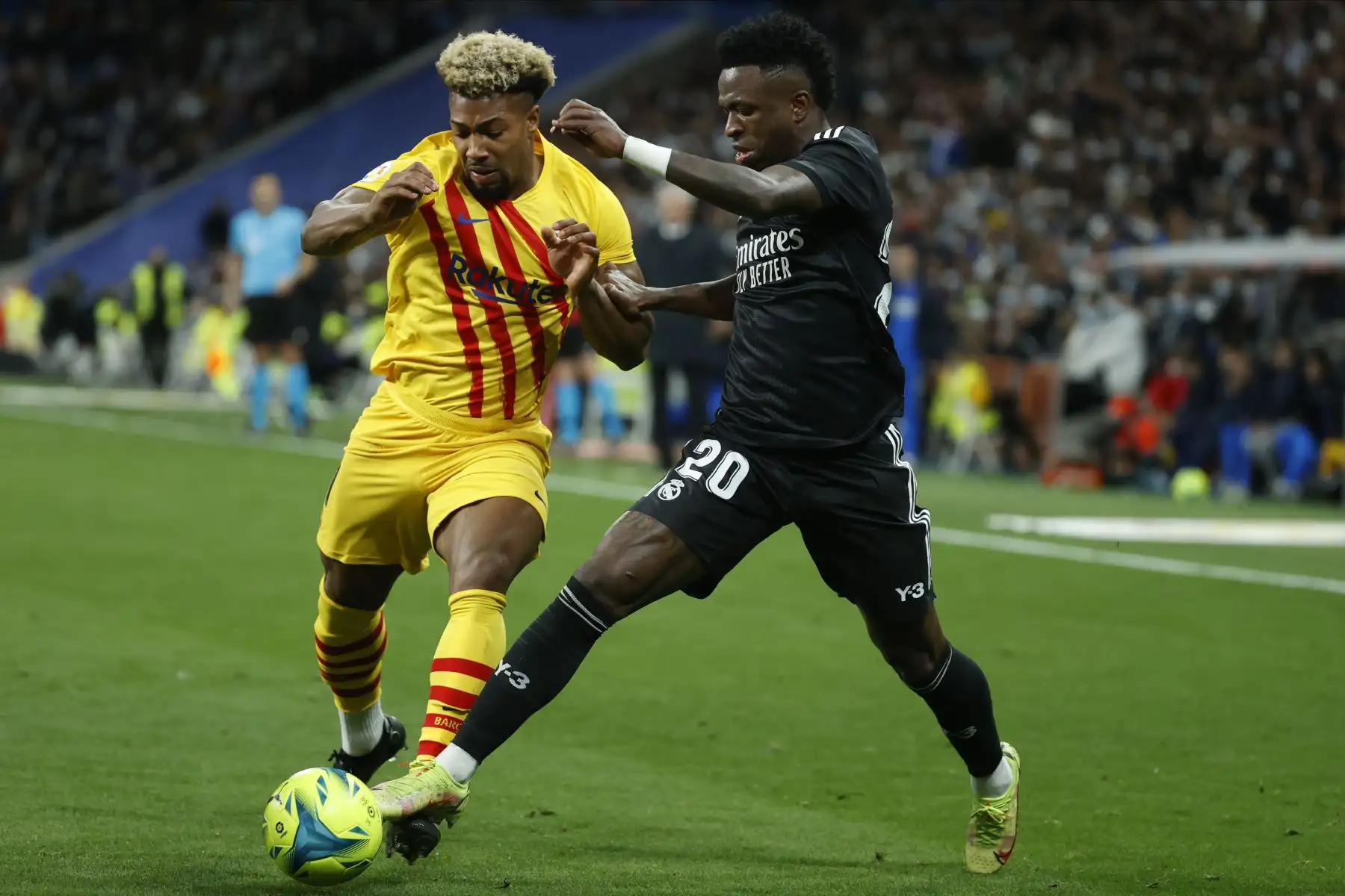 El delantero brasileño del Real Madrid, Vinicius Jr. (d), disputa el balón ante el delantero del FC Barcelona, Adama Traoré, durante el partido de Liga en Primera División que han disputado este domingo en el estadio Santiago Bernabéu, en Madrid. EFE/Juanjo Martín