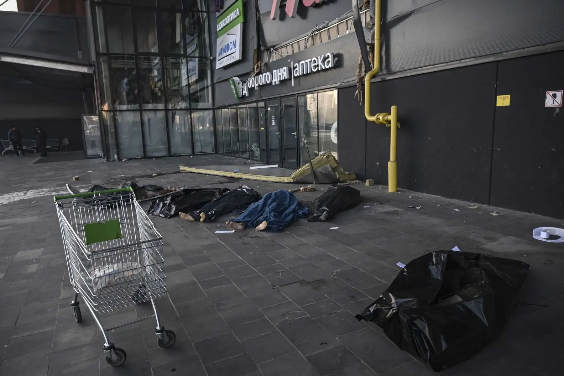 Militares ucranianos están cubiertos con mantas y bolsas de plástico fuera del centro comercial Retroville luego de un ataque con misiles rusos en Kiev. Foto: AFP