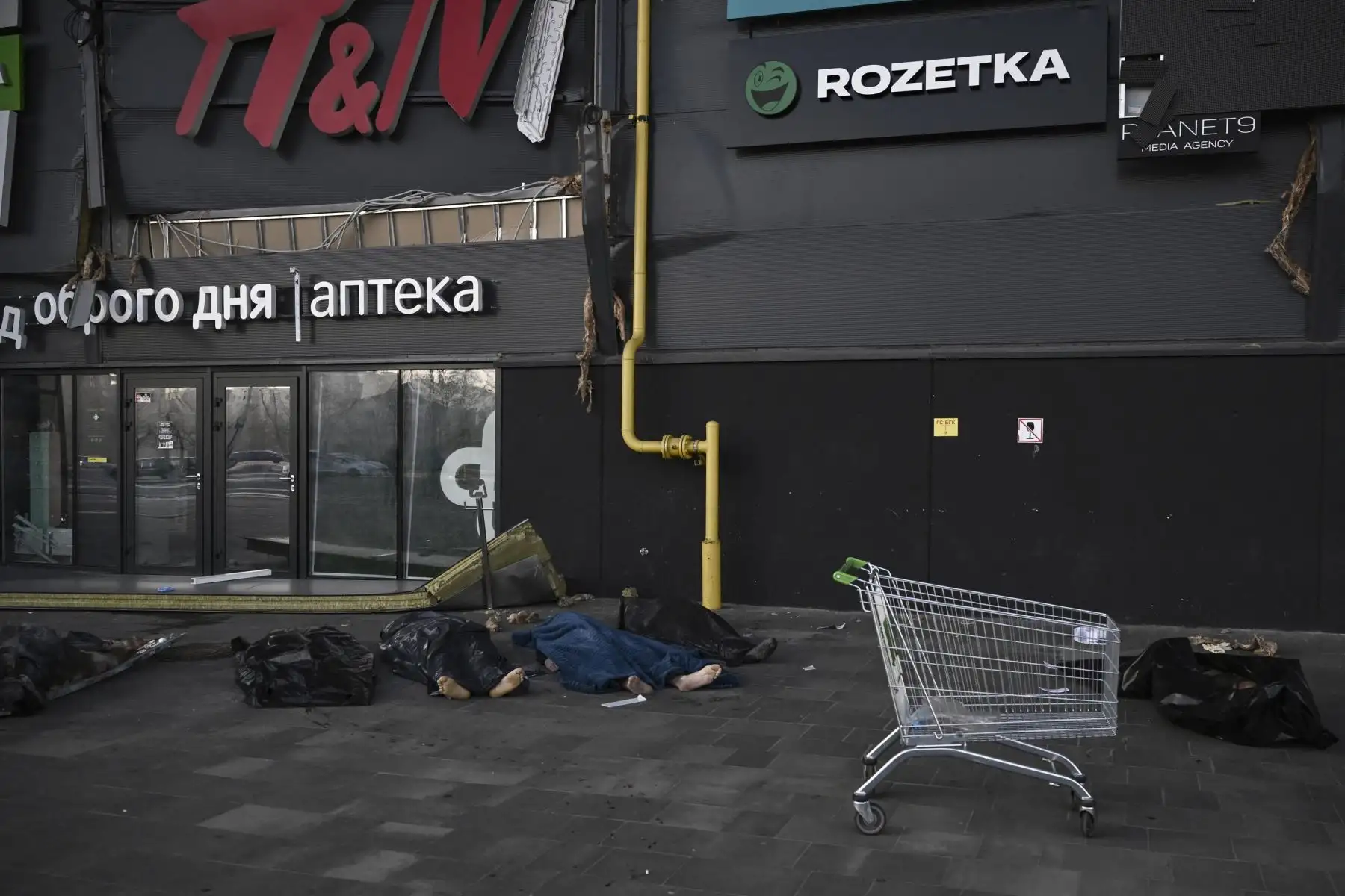 Militares ucranianos están cubiertos con mantas y bolsas de plástico fuera del centro comercial Retroville luego de un ataque con misiles rusos en Kiev. Foto: AFP