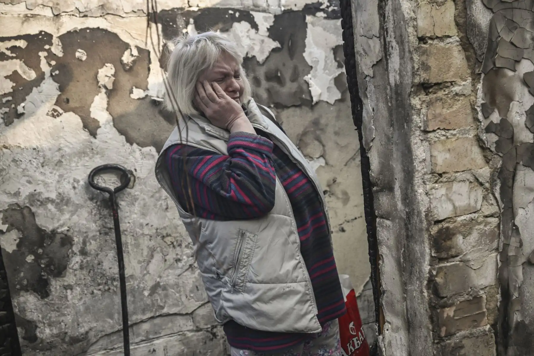 Una mujer reacciona mientras está de pie dentro de una casa incendiada alcanzada por cohetes Grad rusos en el distrito Shevchenkivsky de Kiev. Foto: AFP