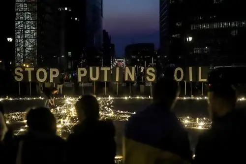 Manifestantes y activistas ucranianos se paran frente a carteles que dicen "Detengan el petróleo de Putin" durante una vigilia por Ucrania cerca de la sede de la Unión Europea (UE) en Bruselas. Foto: AFP.