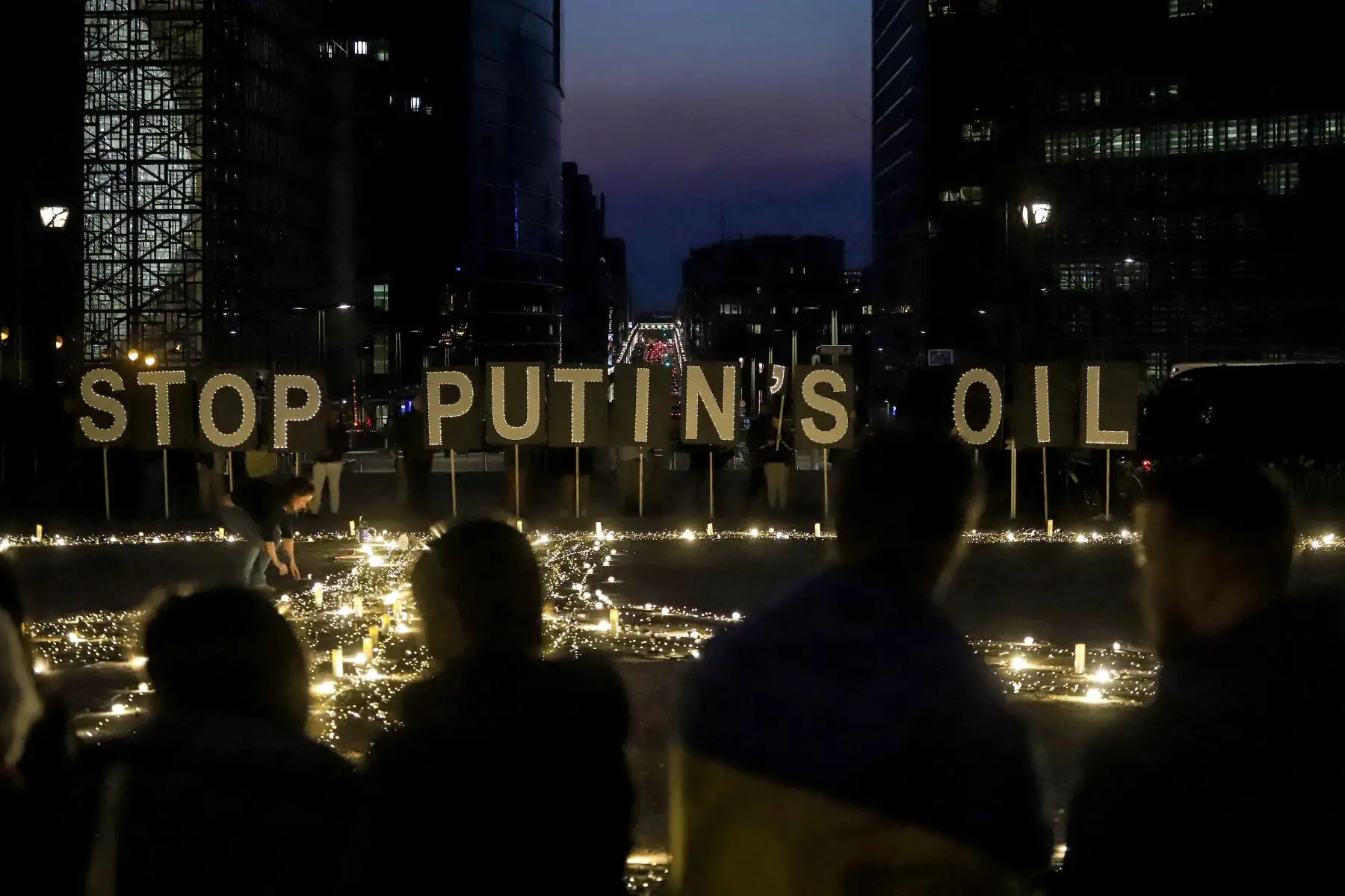 Manifestantes y activistas ucranianos se paran frente a carteles que dicen "Detengan el petróleo de Putin" durante una vigilia por Ucrania cerca de la sede de la Unión Europea (UE) en Bruselas. Foto: AFP.