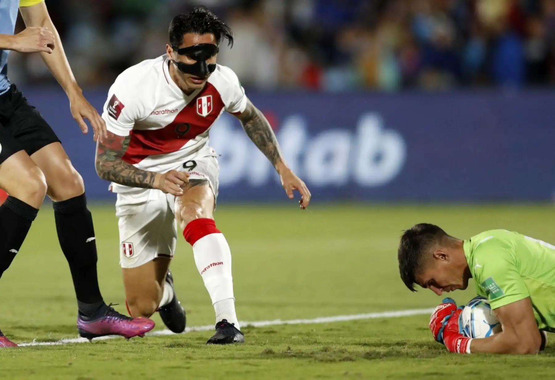El peruano Gianluca Lapadula (izquierda) y el arquero uruguayo Sergio Rochet (derecha) compiten por el balón durante su partido de clasificación sudamericano para la Copa Mundial de la FIFA Qatar 2022 en el estadio Centenario de Montevideo el 24 de marzo de 2022. Foto: AFP