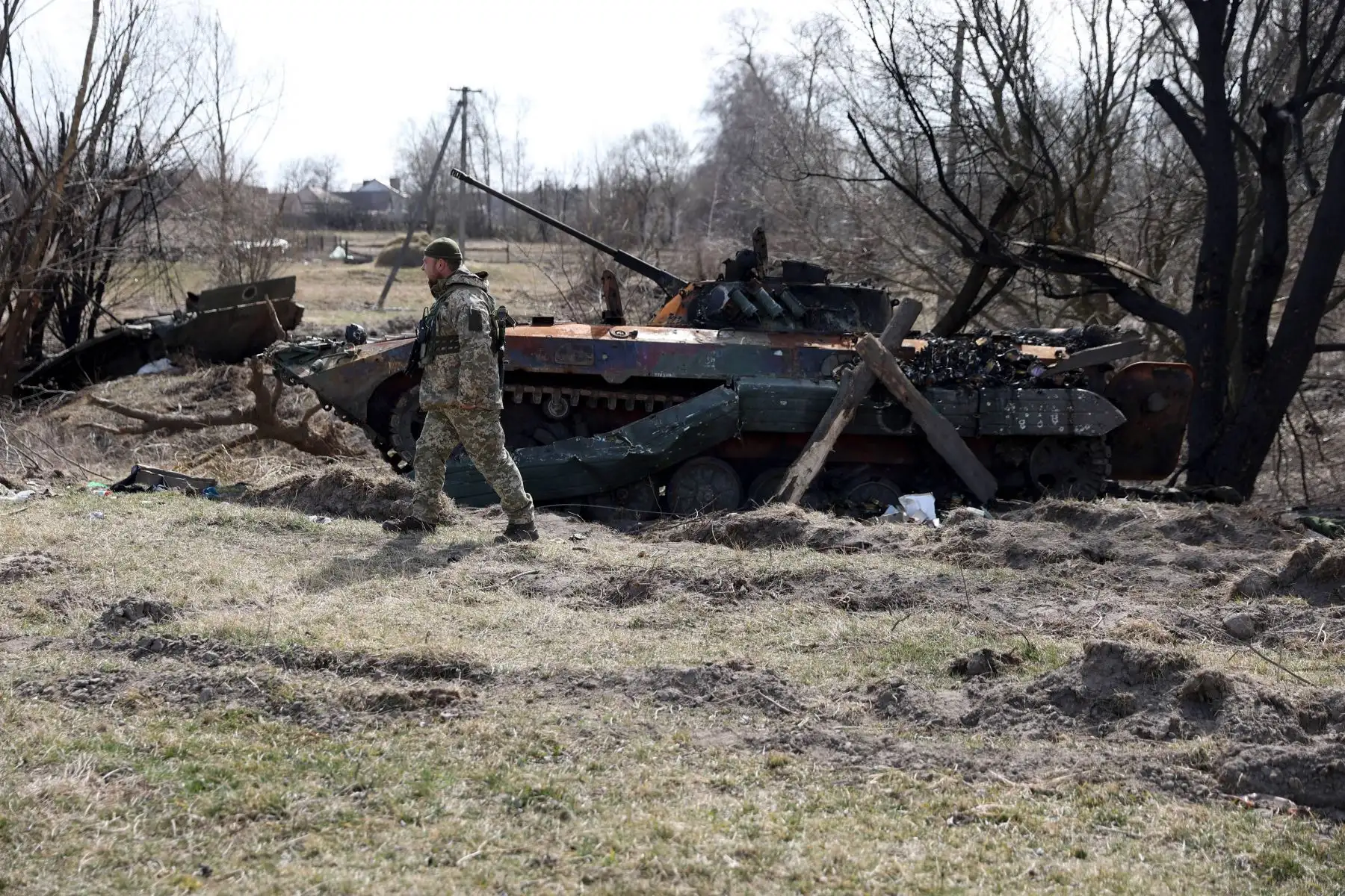 Un soldado ucraniano camina junto a los restos de un transporte personal blindado (APC) en la línea del frente de la parte norte de la región de Kiev. Foto: AFP