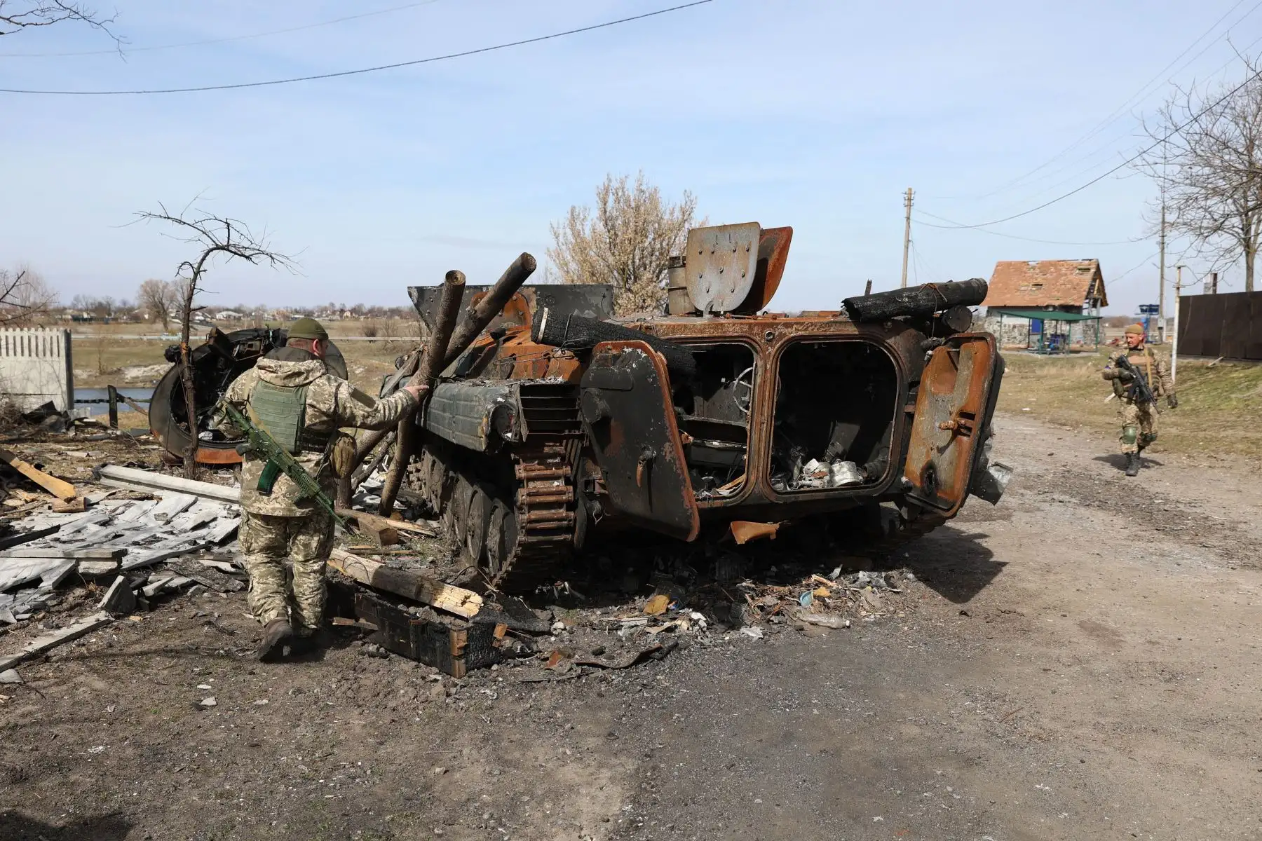 Soldados ucranianos examinan los restos de un vehículo blindado de transporte personal ruso destruido en la línea del frente en la parte norte de la región de Kiev. Foto: AFP