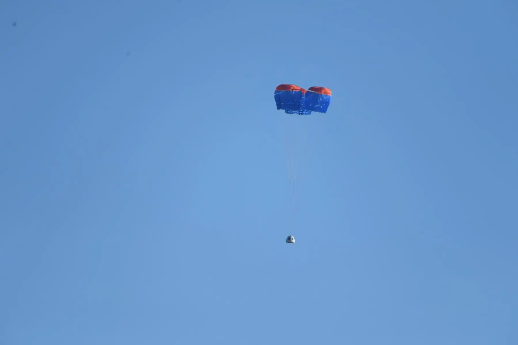 Una cápsula de la tripulación de Blue Origin New Shepard despliega sus paracaídas cuando aterriza en el oeste de Texas al norte de Van Horn. Foto: AFP