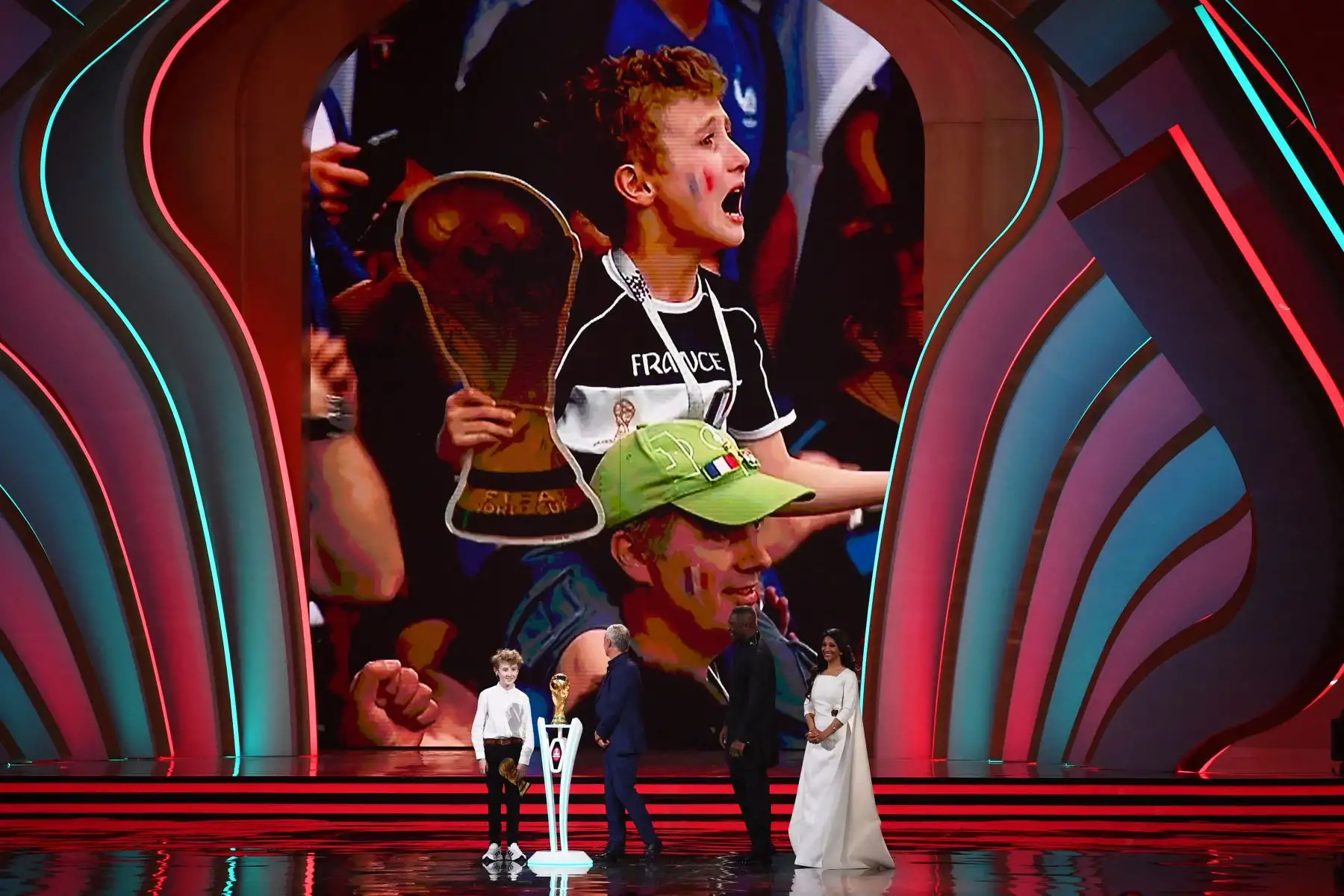 Joris, un niño francés, el entrenador de Francia Didier Deschamps, el actor inglés Idris Elba y el periodista deportivo británico-bangladesí Reshmin Chowdhury con el trofeo de la Copa del Mundo durante el sorteo de la Copa del Mundo de 2022 en Catar en el Centro de Convenciones y Exposiciones de Doha. Foto: AFP