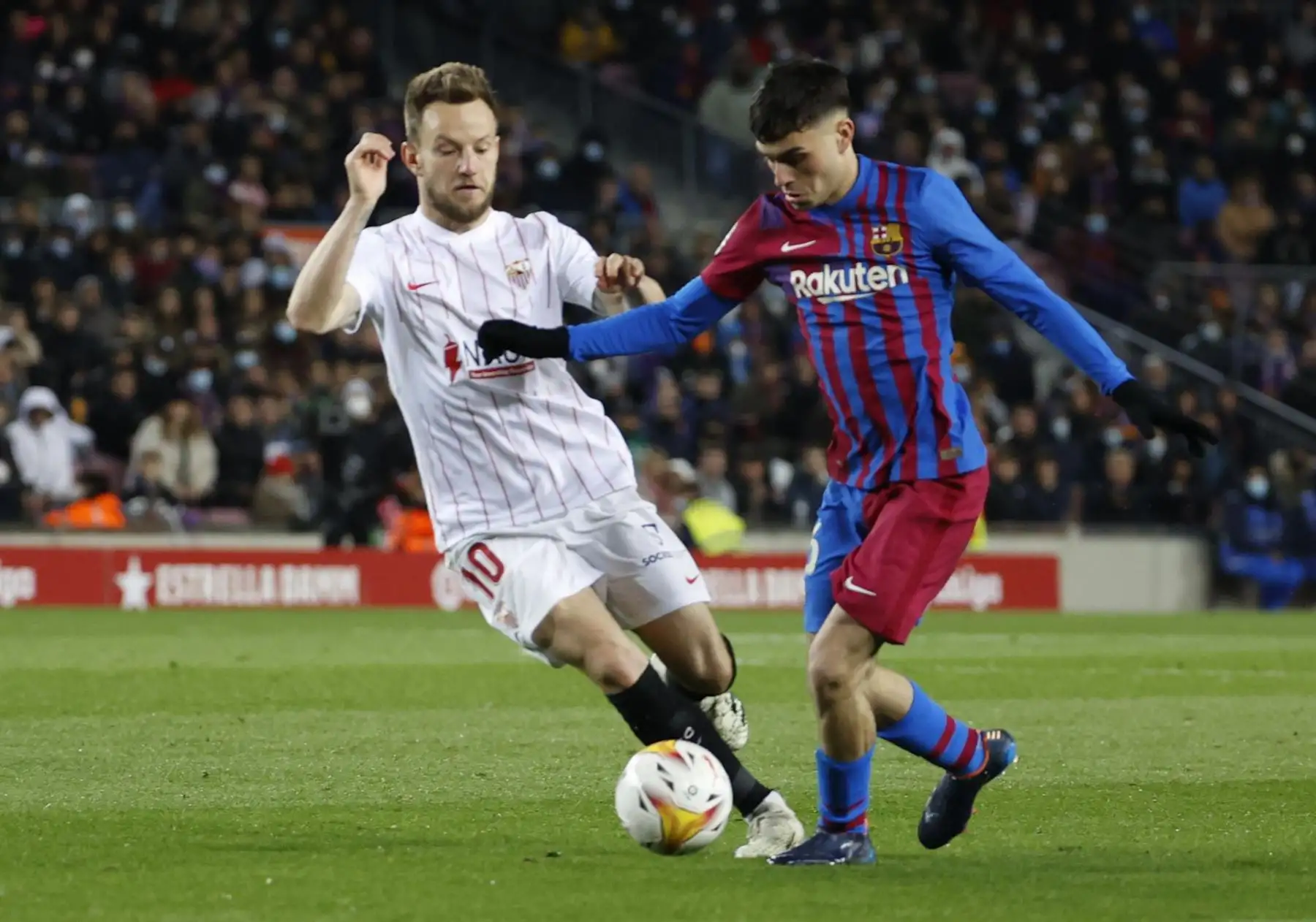 El centrocampista del FC Barcelona Pedro González "Pedri" (d) lucha con el croata Ivan Rakitic, del Sevilla FC, durante el encuentro de la jornada 30 de Liga en Primera División que FC Barcelona y Sevilla FC juegan hoy domingo en el Camp Nou, en Barcelona. EFE/Toni Albir