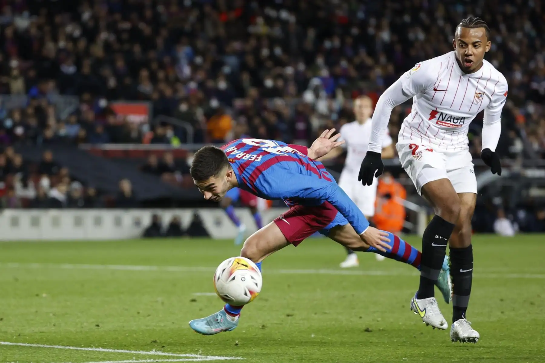 El delantero del FC Barcelona Ferrán Torres (i) lucha con el francés Jules Koundé, del Sevilla FC, durante el encuentro de la jornada 30 de Liga en Primera División que FC Barcelona y Sevilla FC juegan hoy domingo en el Camp Nou, en Barcelona. EFE/Toni Albir