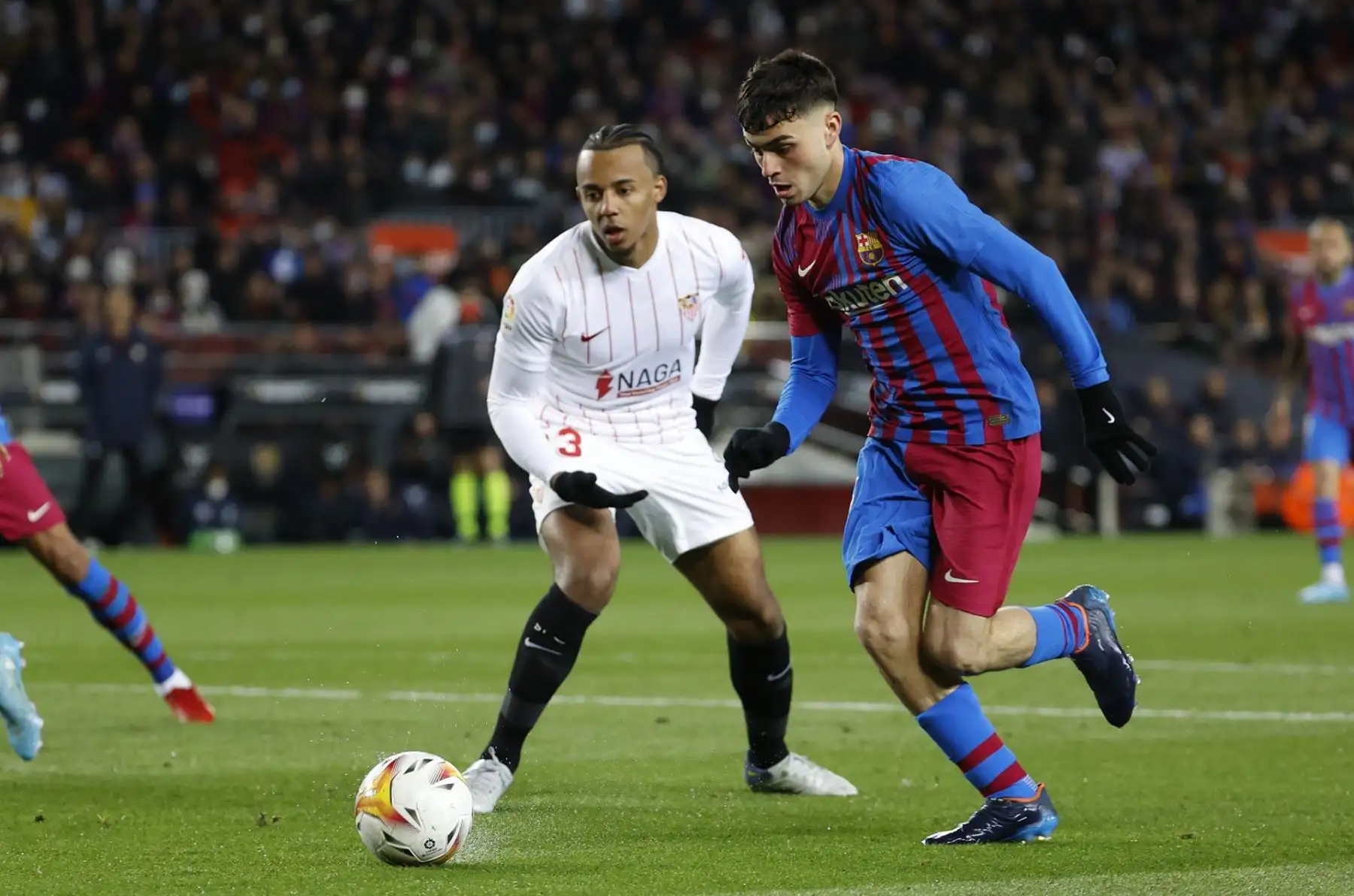 El centrocampista del FC Barcelona Pedro González "Pedri" (d) intenta escaparse del francés Jules Koundé, del Sevilla FC, durante el encuentro de la jornada 30 de Liga en Primera División que FC Barcelona y Sevilla FC juegan hoy domingo en el Camp Nou, en Barcelona. EFE/Toni Albir