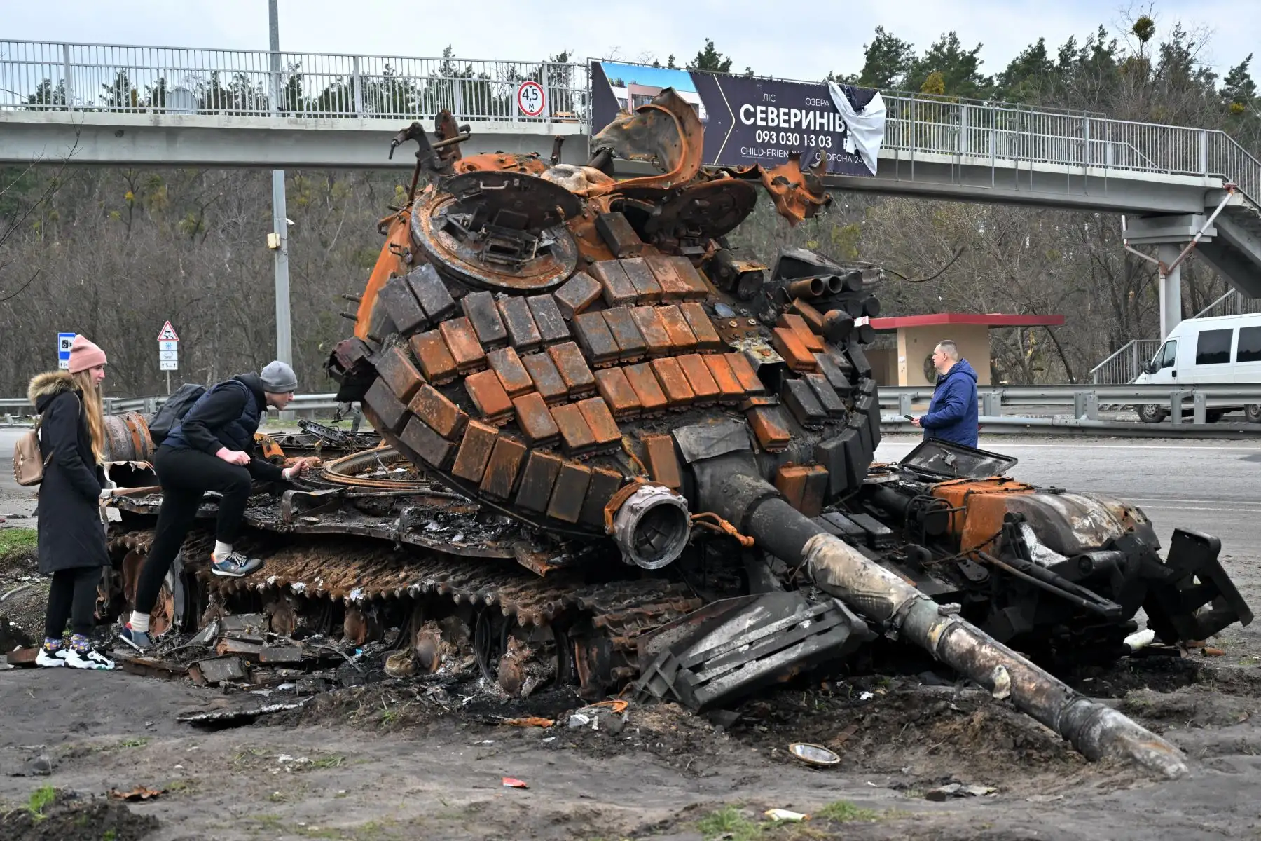 Residentes observan un tanque ruso destruido en las afueras de la aldea de Buzova, al oeste de Kiev. Foto: AFP