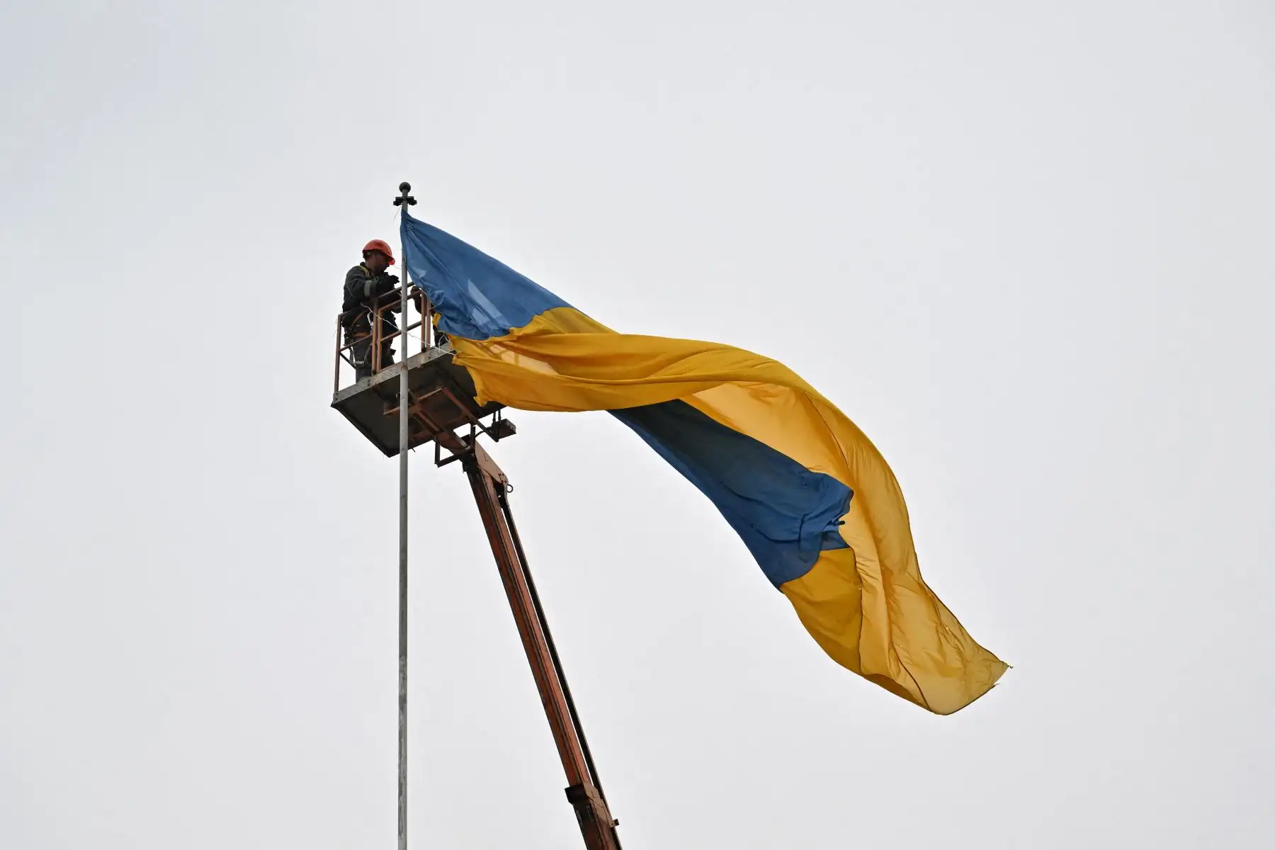 Trabajadores colocan una bandera ucraniana en un asta en el centro de Makariv, región de Kiev. Foto: AFP