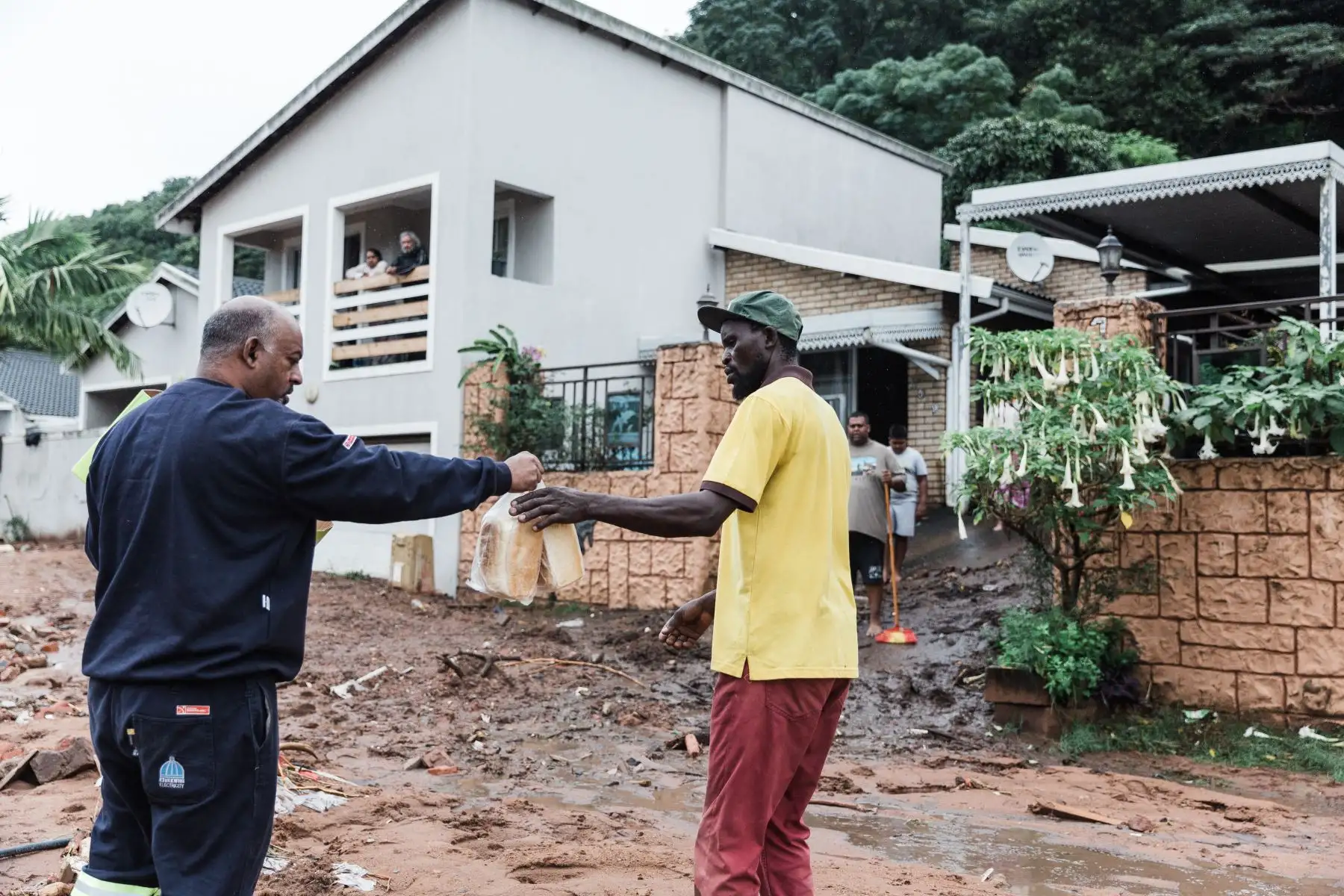 Un voluntario local entrega dos hogazas de pan a quienes necesitan alimentos luego de fuertes lluvias y vientos en Durban, el 12 de abril de 2022. 
Foto: ANDINA/AFP