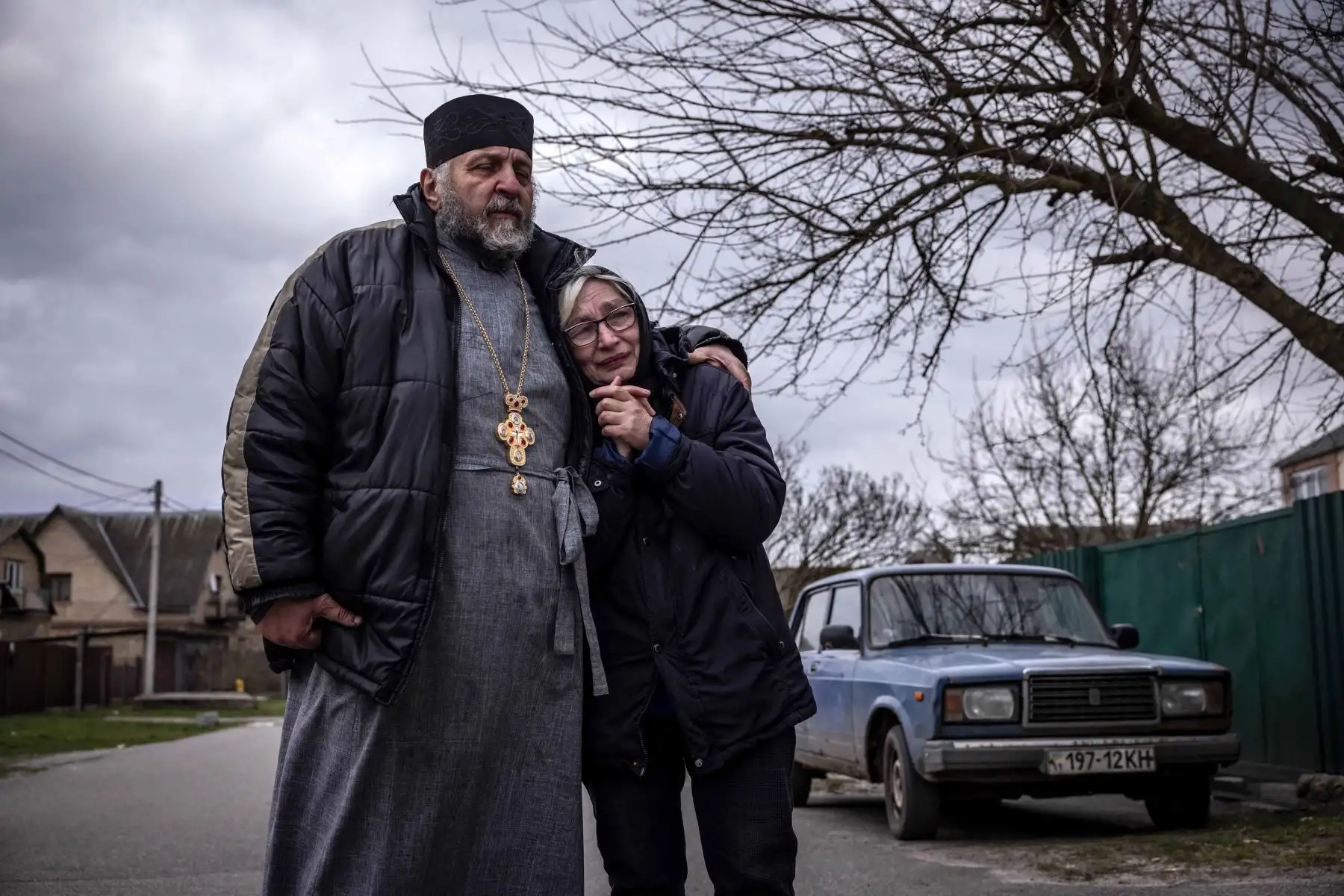 Un sacerdote y un pariente de un civil exhumado de su patio reaccionan en la aldea de Gostomel, región de Kiev. Foto: AFP