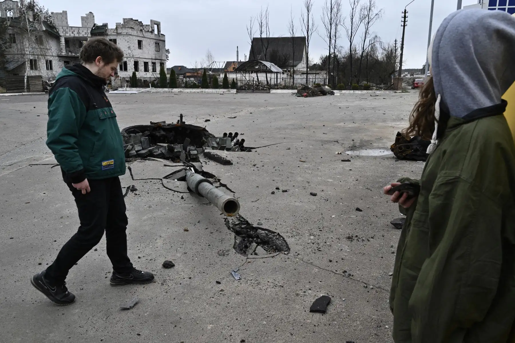 La gente camina junto a los escombros de un tanque ruso destruido cerca de la aldea de Zalissya, al noreste de Kiev. Foto: AFP