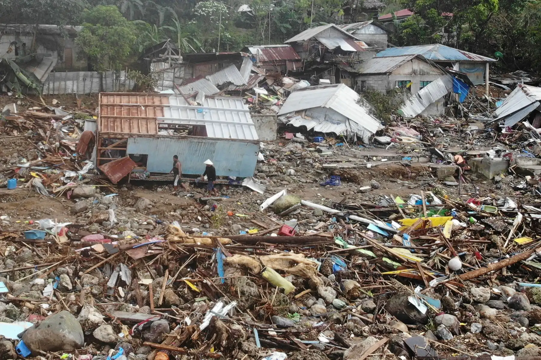 Residentes caminan frente a casas destruidas en el pueblo de Pilar, ciudad de Abuyog, provincia de Leyte, un día después de que un deslizamiento de tierra azotara el pueblo debido a las fuertes lluvias en el punto álgido de la tormenta tropical Megi. Foto: AFP