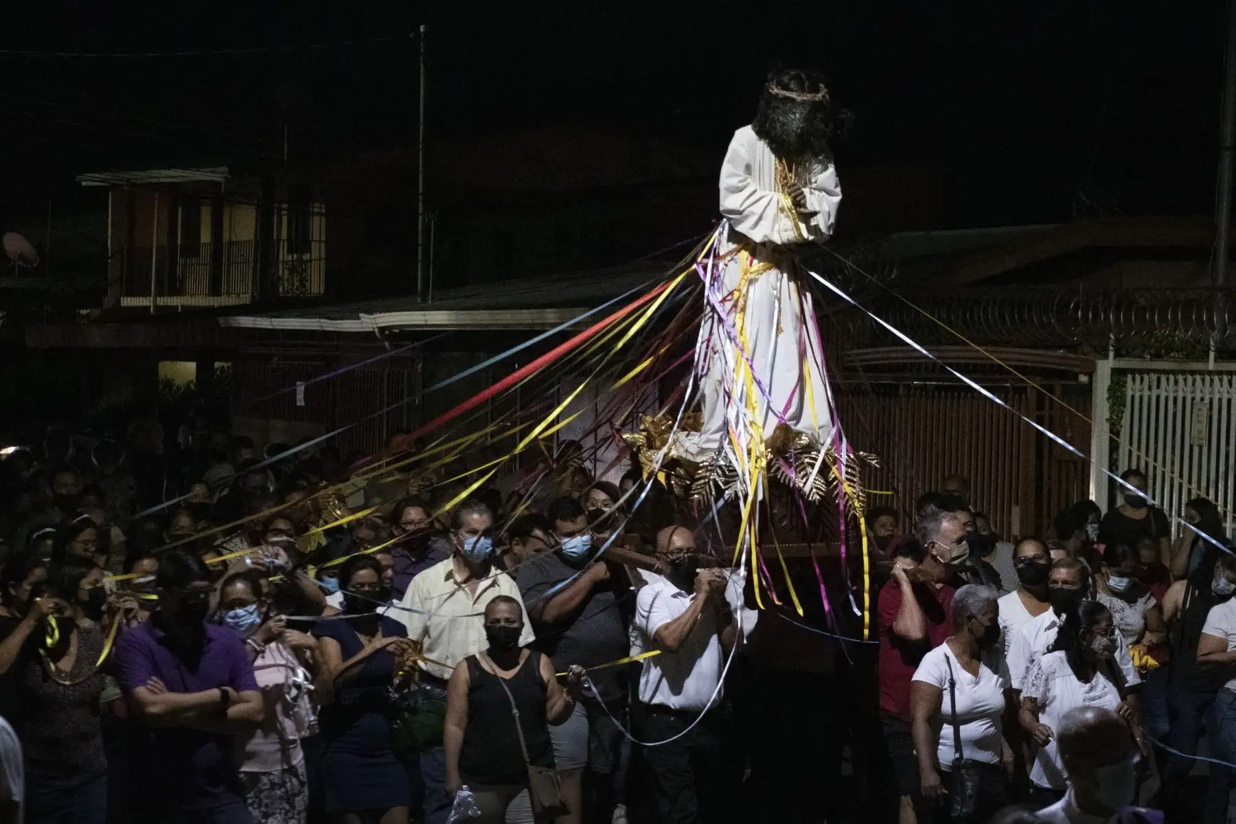 Fieles católicos sostienen cintas de colores atadas a una estatua de Jesús Nazareno, mientras asistían a una misa en la iglesia San José Patriarca en Costa Rica. Foto: AFP