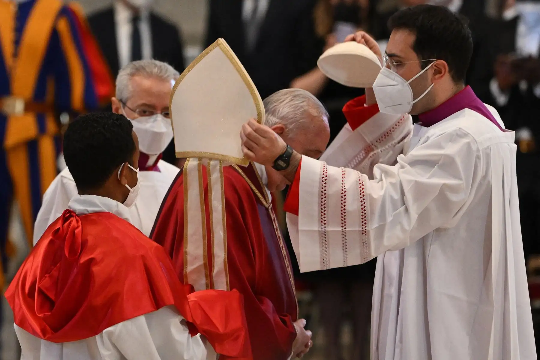 Un sacerdote cambia la mitra del Papa Francisco por un casquete al comienzo de la Liturgia de la Pasión del Señor el Viernes Santo, en la Basílica de San Pedro en el Vaticano. Foto: AFP