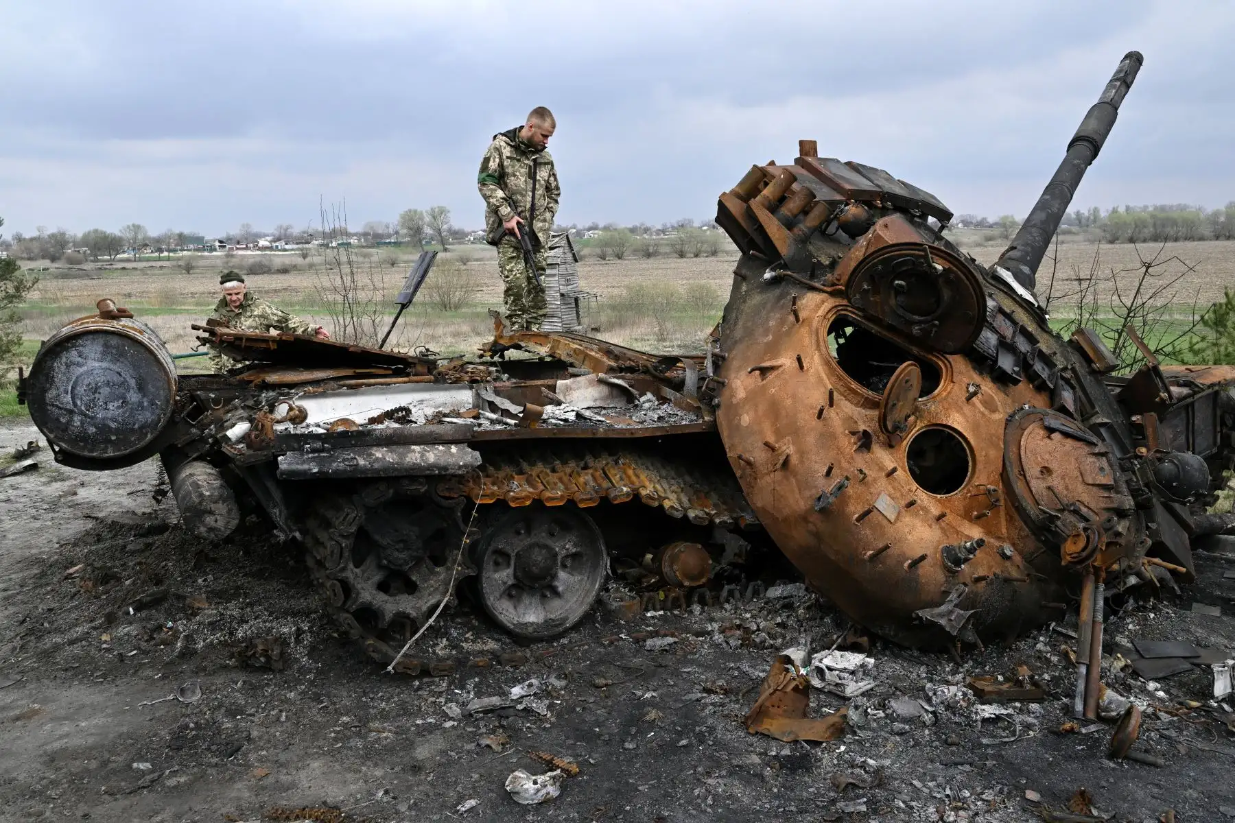 Militares ucranianos miran un tanque ruso destruido en una carretera en la aldea de Rusaniv. Foto: AFP