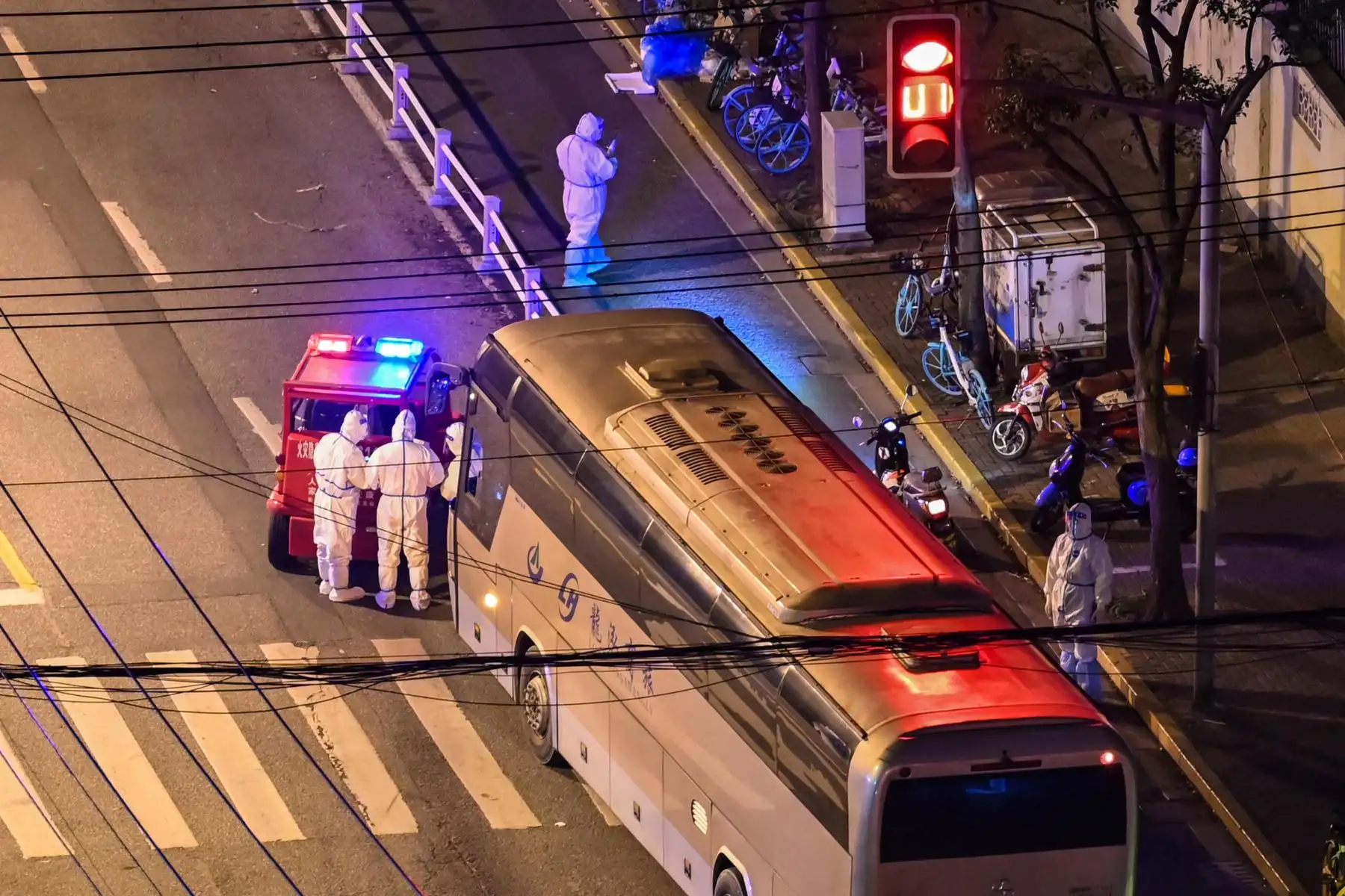 Trabajadores que usan equipo de protección personal (EPP) se paran junto a un autobús en una calle durante un bloqueo de coronavirus Covid-19 en  Shanghai. Foto: AFP