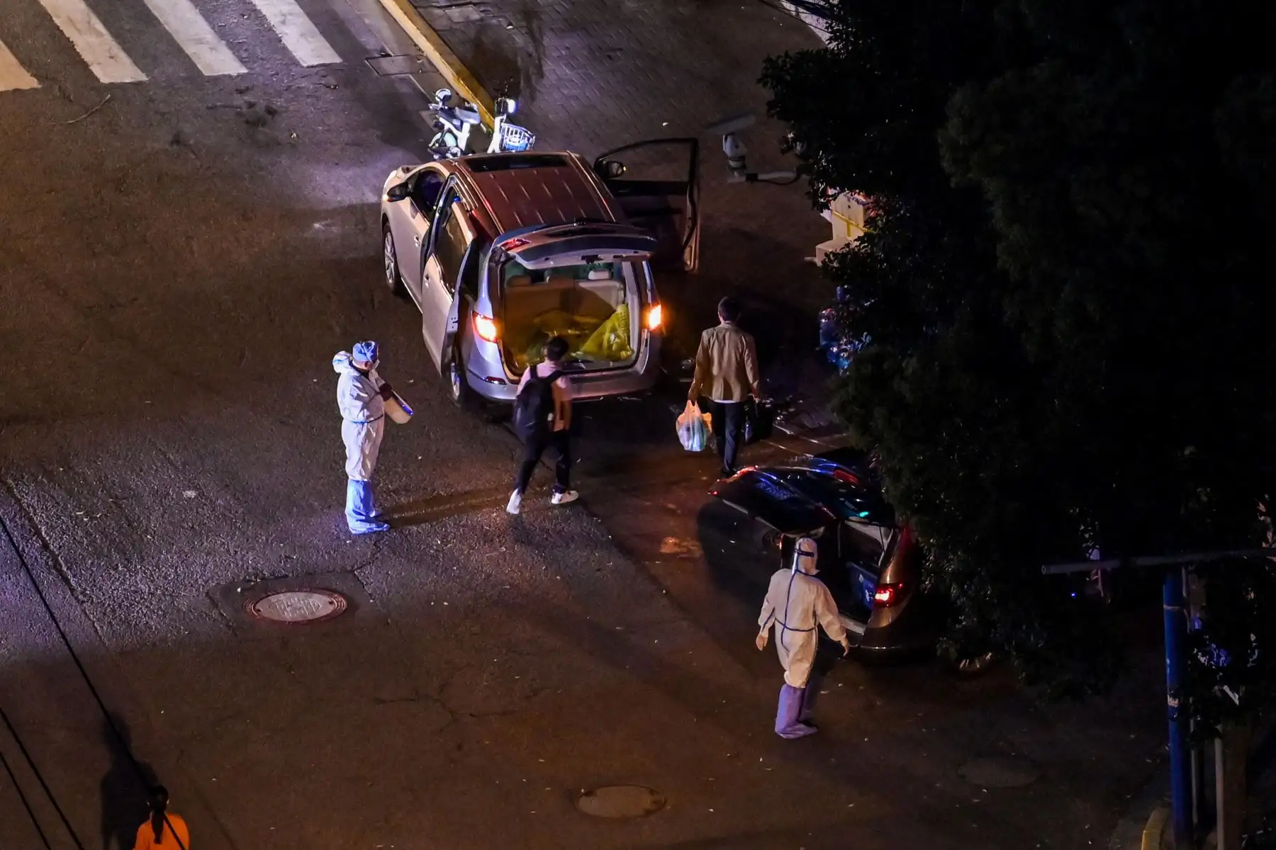 Trabajadores que usan equipo de protección personal (EPP) se paran junto a un vehículo en una calle durante un bloqueo de coronavirus Covid-19 en  Shanghai. Foto: AFP