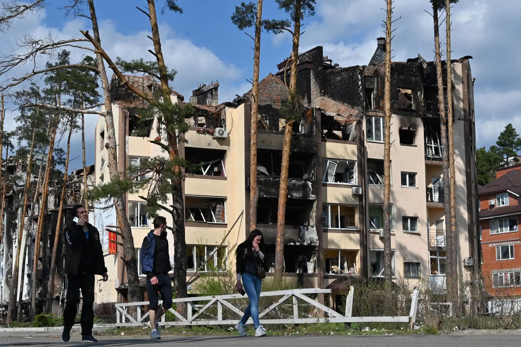 Peatones pasan frente a un edificio residencial destruido en Irpin, al noroeste de Kiev, en medio de la invasión rusa de Ucrania. Foto: AFP