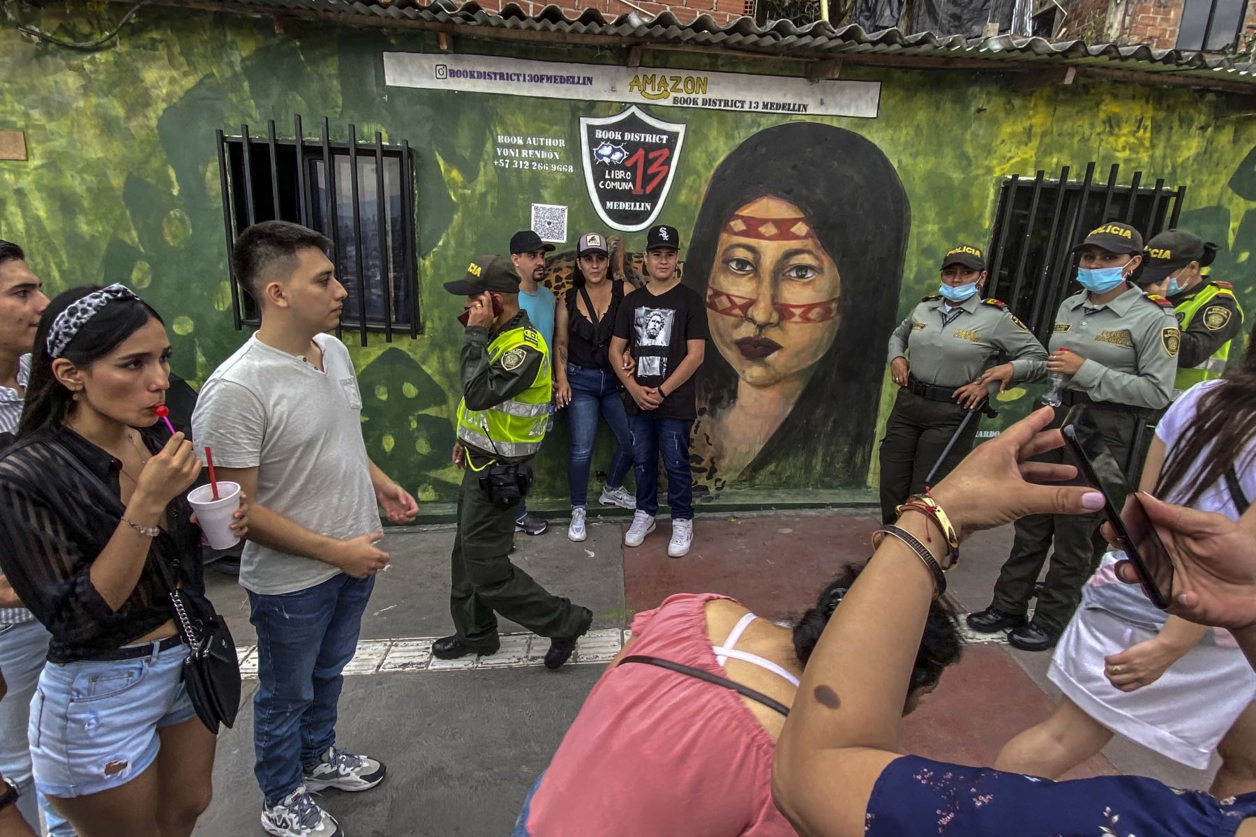 Turistas caminan por un mural mientras visitan Medellín, Colombia. Foto: AFP