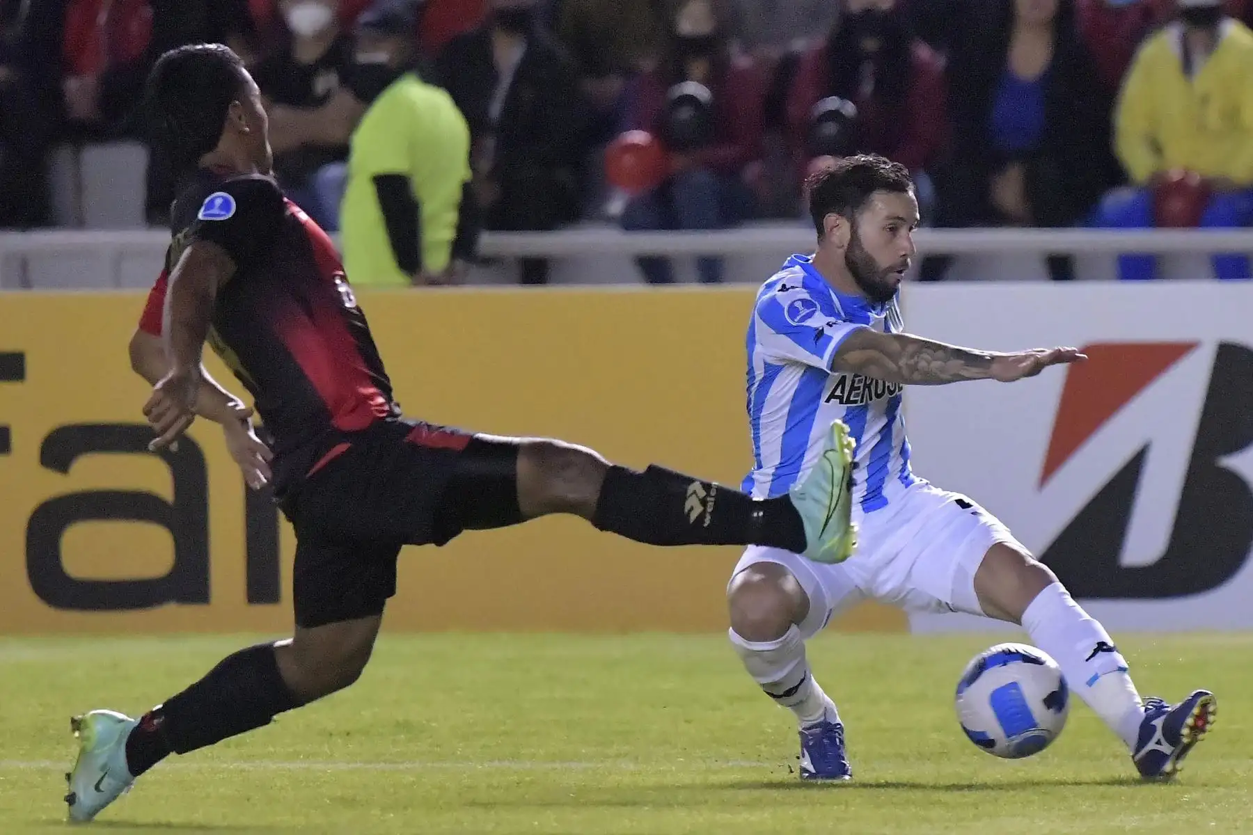 Eugenio Mena de  Racing y Alejandro Ramos de Melgar, compiten por el balón durante su partido de fútbol de la fase de grupos de la Copa Sudamericana en el estadio Monumental de la UNSA en Arequipa. Foto: AFP